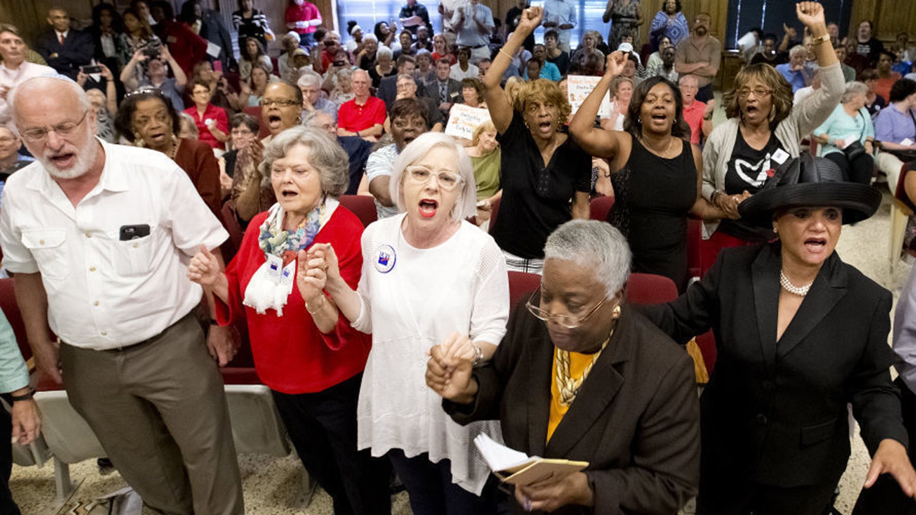 In this Aug. 9, 2016 file photo, people rise and begin singing during the Guilford County Board of Elections meeting at the Old Guilford County Courthouse in Greensboro, N.C.