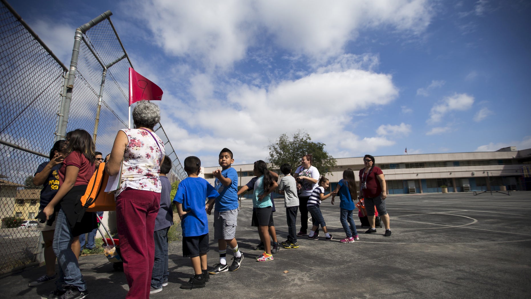 A teacher holds a flag as she evacuates with her students during the "Great ShakeOut" earthquake drill at Marlton School in Los Angeles, California October 15, 2015. (REUTERS/Mario Anzuoni)