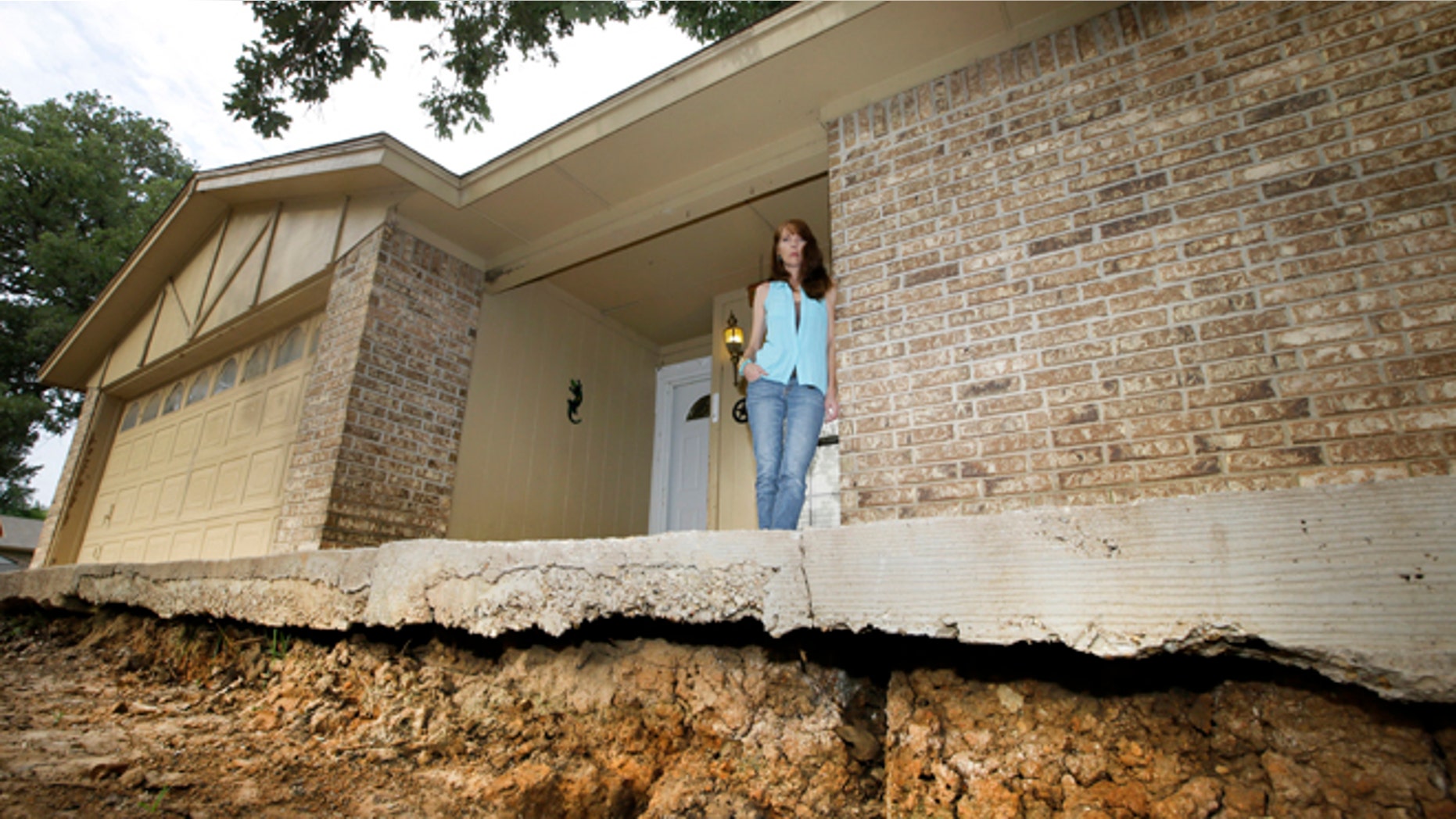 June 21, 2014: Barbara Brown poses for a photo on the front step of her home that now sits about one foot off the surface of her lawn.