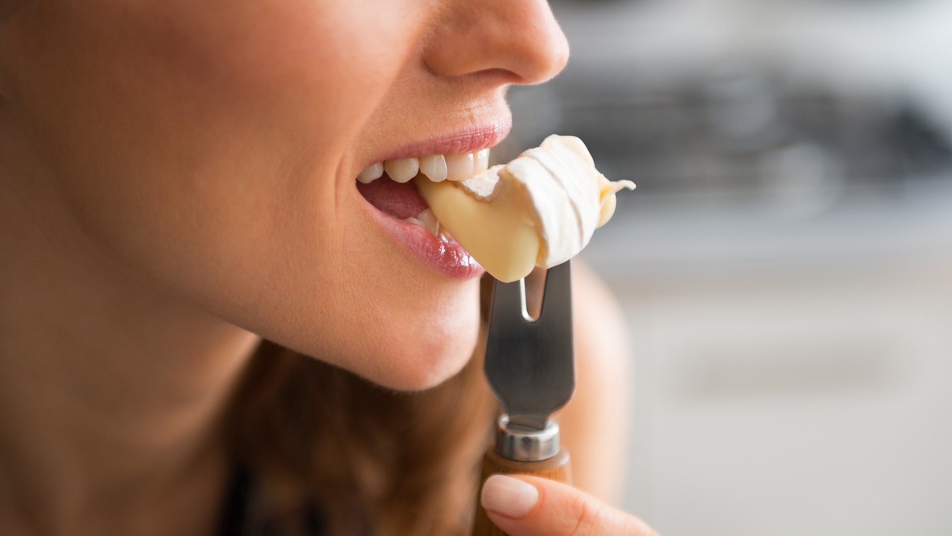 Closeup on young woman eating camembert