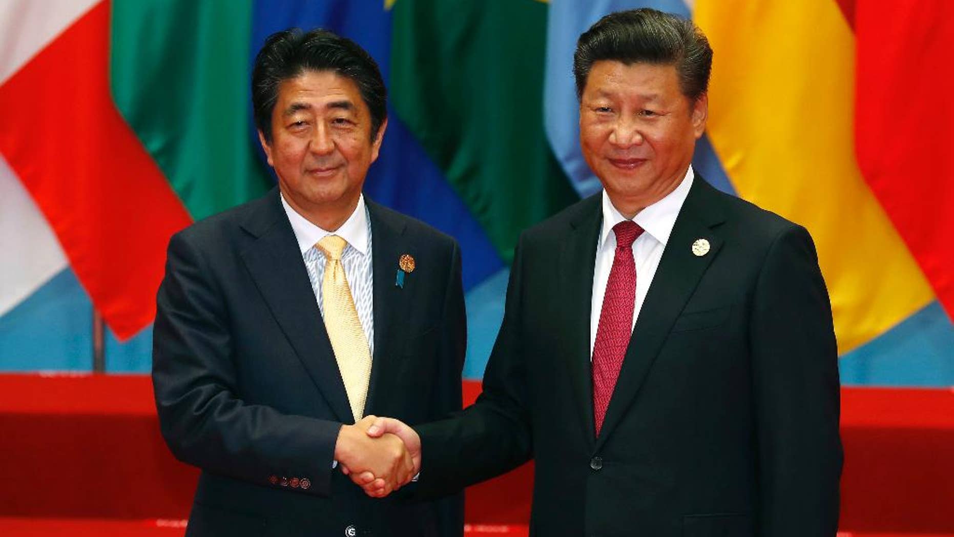 FILE- In this Sunday, Sept. 4, 2016, file photo, Japan's Prime Minister Shinzo Abe, left, poses with China's President Xi Jinping for a photo before a group photo session for the G20 Summit in Hangzhou in eastern China's Zhejiang province. Four years after they went into a nosedive, tense relations between China and Japan may finally be headed for a sustained return to some semblance of normalcy. Those hopes rest largely on a statement by Chinese President Xi Jinping at a meeting Monday with Japanese Prime Minister Shinzo Abe that it was time to “put aside disruptions" and bring ties “back on the normal track.” (AP Photo/Ng Han Guan, File)