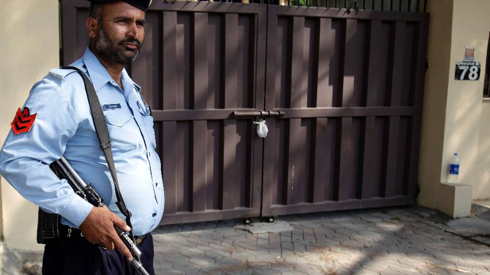 A Pakistani police officer stands guard outside a sealed office of international aid group Save the Children , in Islamabad, Pakistan, Sunday, June 14, 2015. Pakistan's Interior Ministry has halted an order it made closing the office of Save the Children in Islamabad, an official said Sunday. On Thursday, Pakistan shuttered the group's main office in the capital for allegedly "violating its charter." (AP Photo/Anjum Naveed)