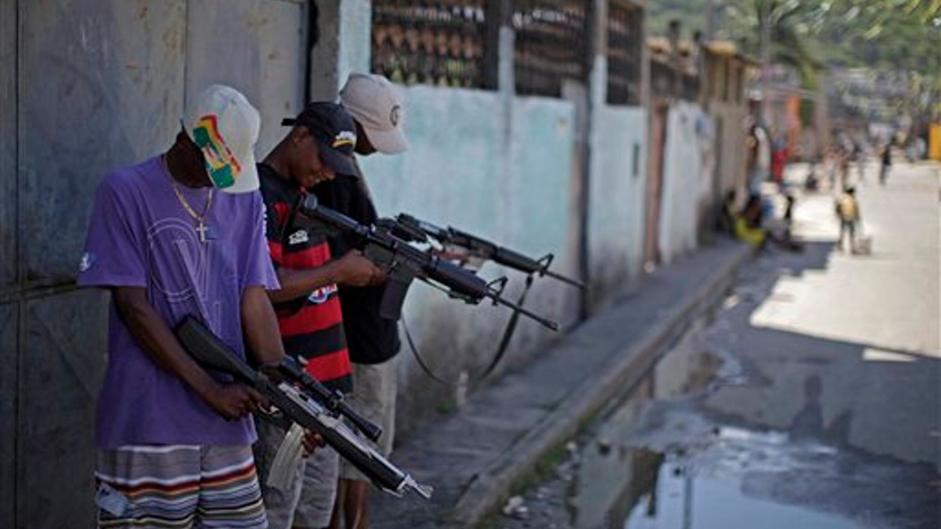 Nov. 27: Alleged drug traffickers who did not want to identify themselves, hold their weapons while posing for a photo at a slum in western Rio de Janeiro, Brazil.