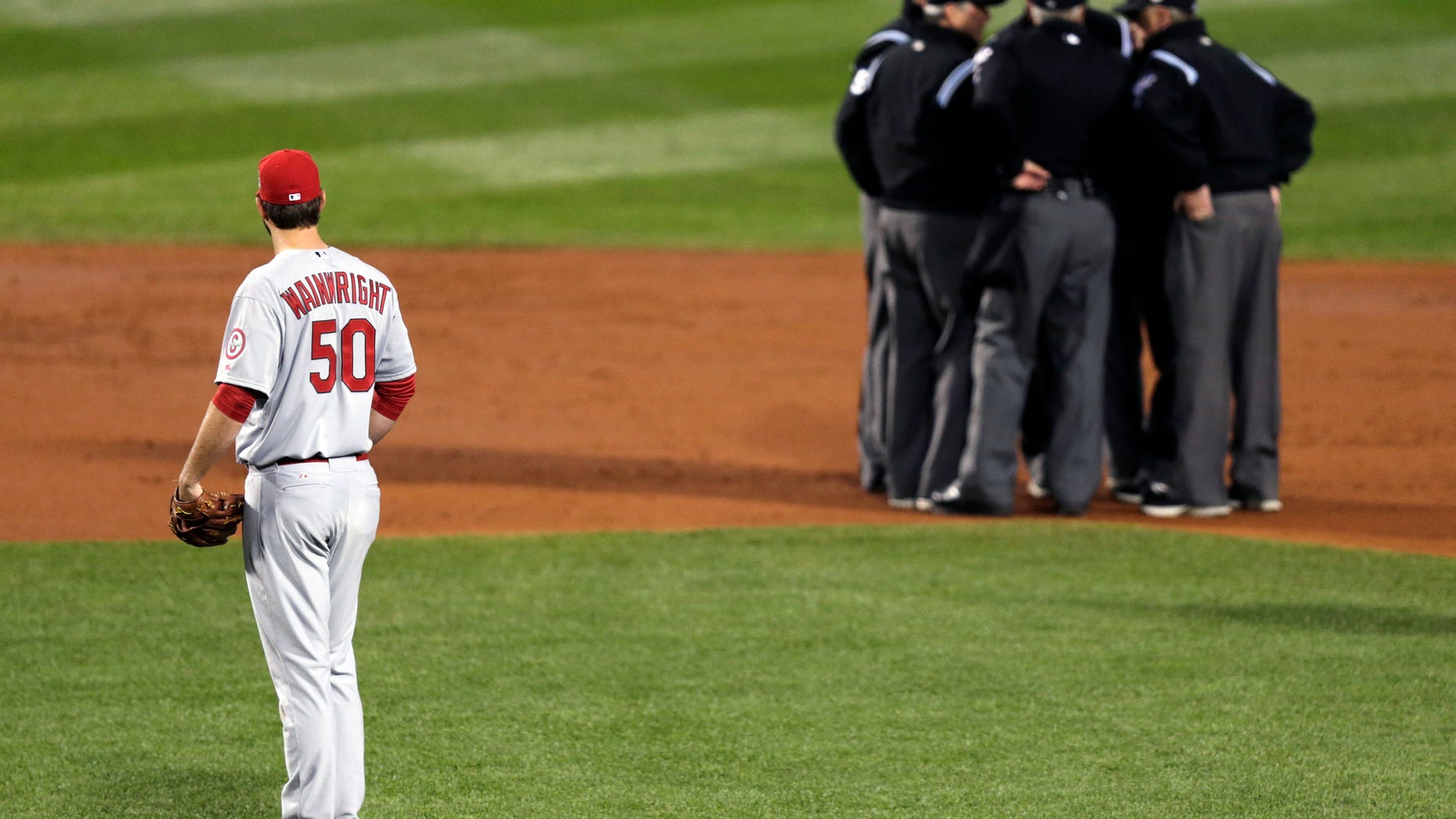 FILE - In this Oct. 23, 2013, file photo, St. Louis Cardinals starting pitcher Adam Wainwright watches as umpires discuss a ruling during the first inning of Game 1 of baseball's World Series against the Boston Red Sox in Boston. Major League Baseball announced Thursday, Jan. 16, 2014, that it will greatly expand instant replay to review close calls starting this season. Each manager will be allowed to challenge at least one call per game. If he's right, he gets another challenge. After the seventh inning, a crew chief can request a review on his own. (AP Photo/Charles Krupa, File)
