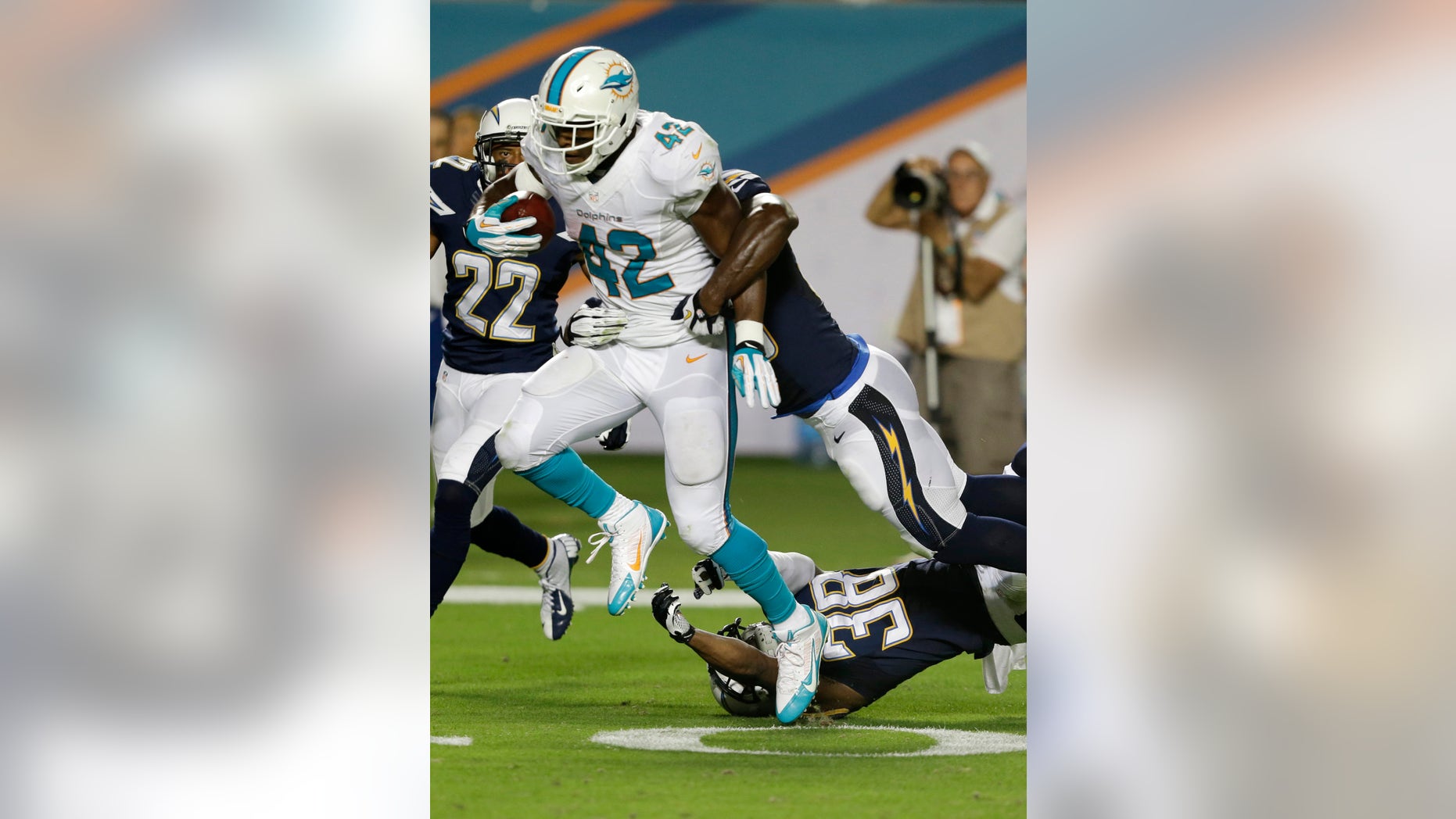 Miami Dolphins tight end Charles Clay (42) breaks up tackles by San Diego Chargers strong safety Marcus Gilchrist (38) and linebacker Donald Butler (56) for a 39-yard run for a touchdown during the second half of an NFL football game, Sunday, Nov. 17, 2013, in Miami Gardens, Fla. (AP Photo/Wilfredo Lee)