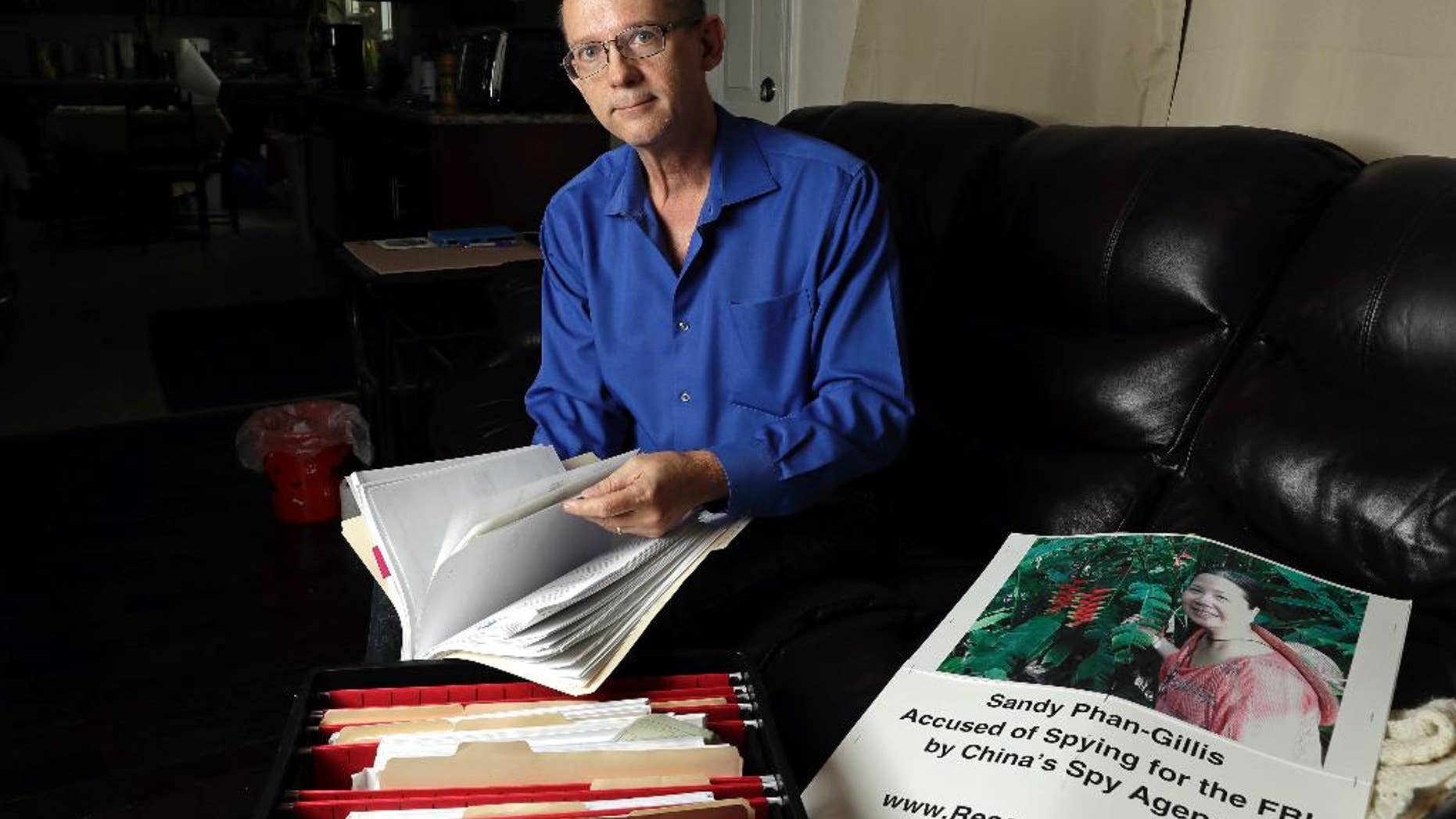 FILE - In this Oct. 4, 2016, file photo, Jeff Gillis looks through documents he has collected in support of his wife in Houston. The husband of U.S. citizen Phan "Sandy" Phan-Gillis, who has been charged in China with spying, has spent months trying to prove his wife's innocence with the little information he had. A Chinese court on Tuesday, April 25, 2017, sentenced Phan-Gillis to 3 ½ years in prison for spying charges, in a case that has drawn criticism from the United Nations and human rights advocates. (AP Photo/David J. Phillip, File)
