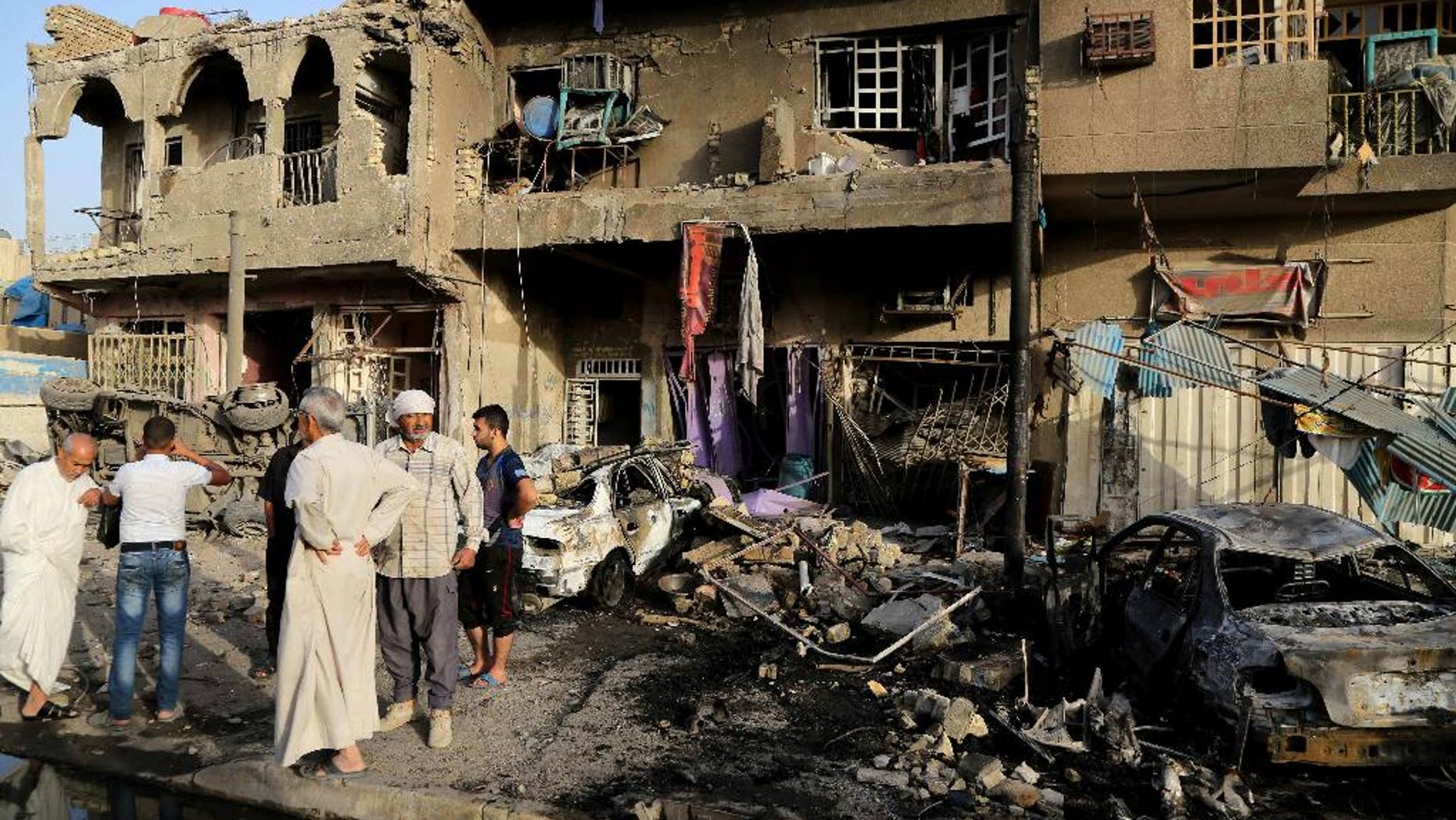 Oct. 1, 2014: Civilians inspect the site of double car bombings in the northern Shiite district al-Hurriyah in Baghdad, Iraq. On Tuesday, officials say a wave of bombings targeted commercial areas across Iraq, killing and wounding dozens of people.