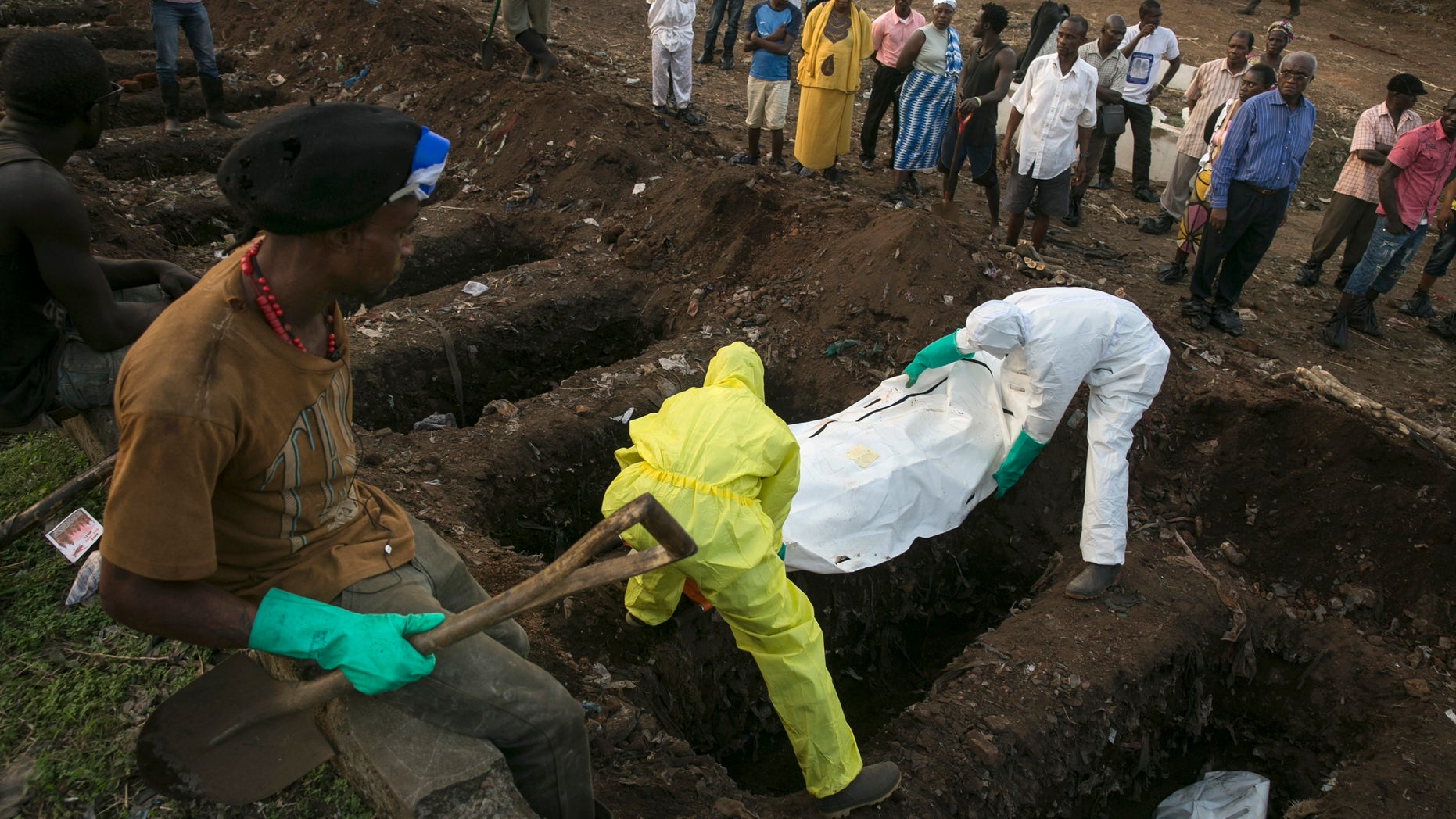 A grave digger watches as health workers carry the body of an Ebola victim for burial at a cemetery in Freetown December 17, 2014. REUTERS/Baz Ratner