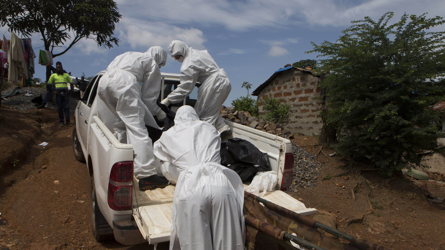 A burial team wearing protective clothing, remove a body of a person suspected of having died of the Ebola virus, in Freetown September 28, 2014. REUTERS/Christopher Black/WHO/Handout via Reuters