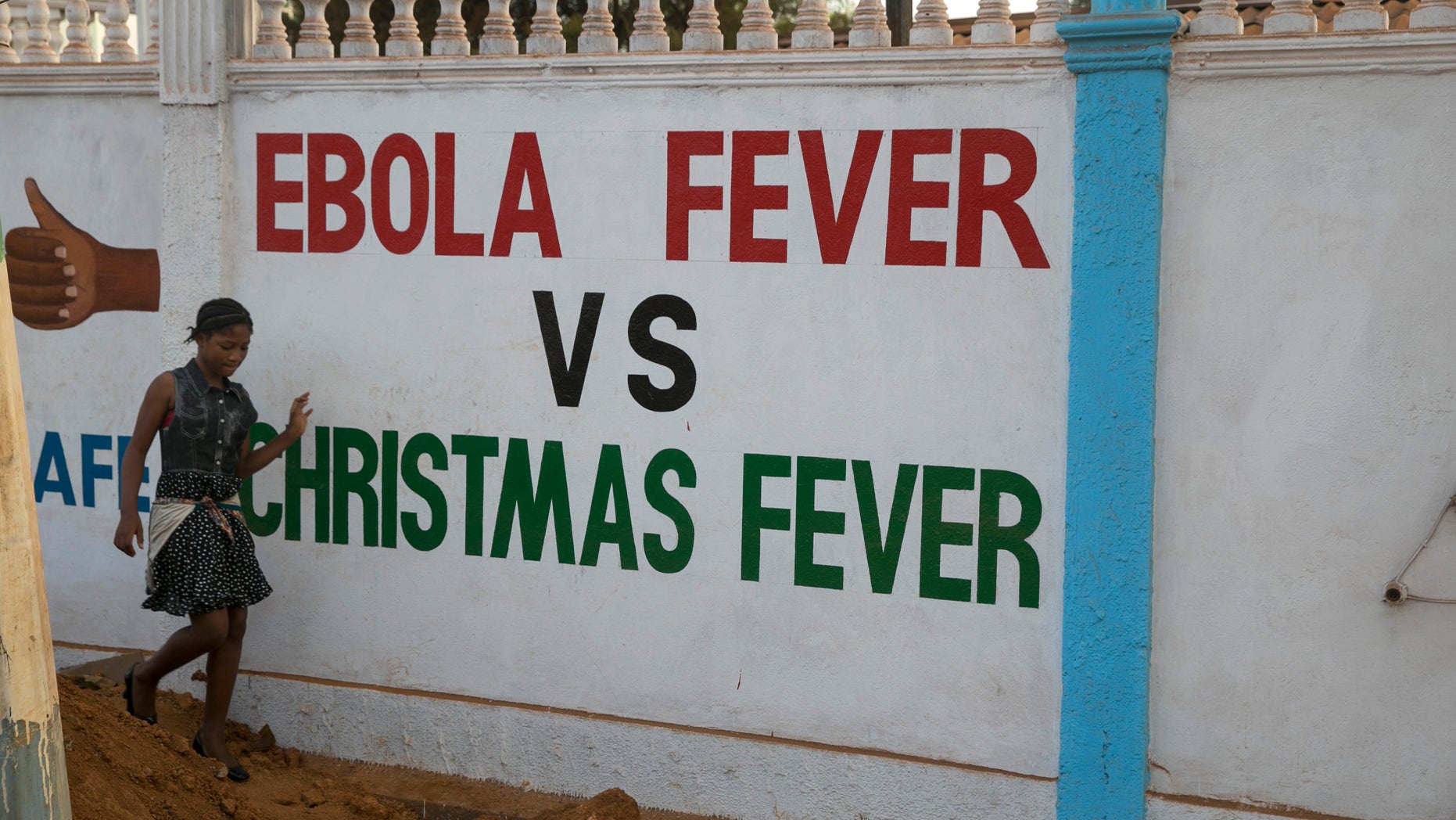A girl walks past a a sign in Freetown December 21, 2014. REUTERS/Baz Ratner