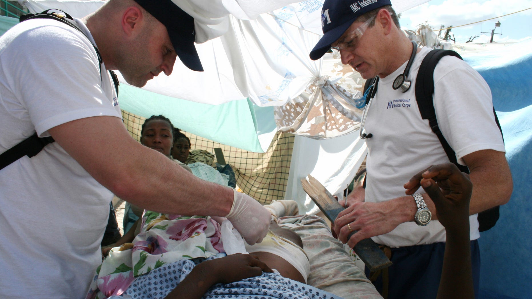 In this Jan. 16, 2010 photo provided by the International Medical Corps, Dr. Robert Fuller, right, joins Dr. Matthew Howell as they care for a person injured in the 2010 earthquake in Port-ua-Prince, Haiti. AP Photo/International Medical Corps, Margaret Aguirre