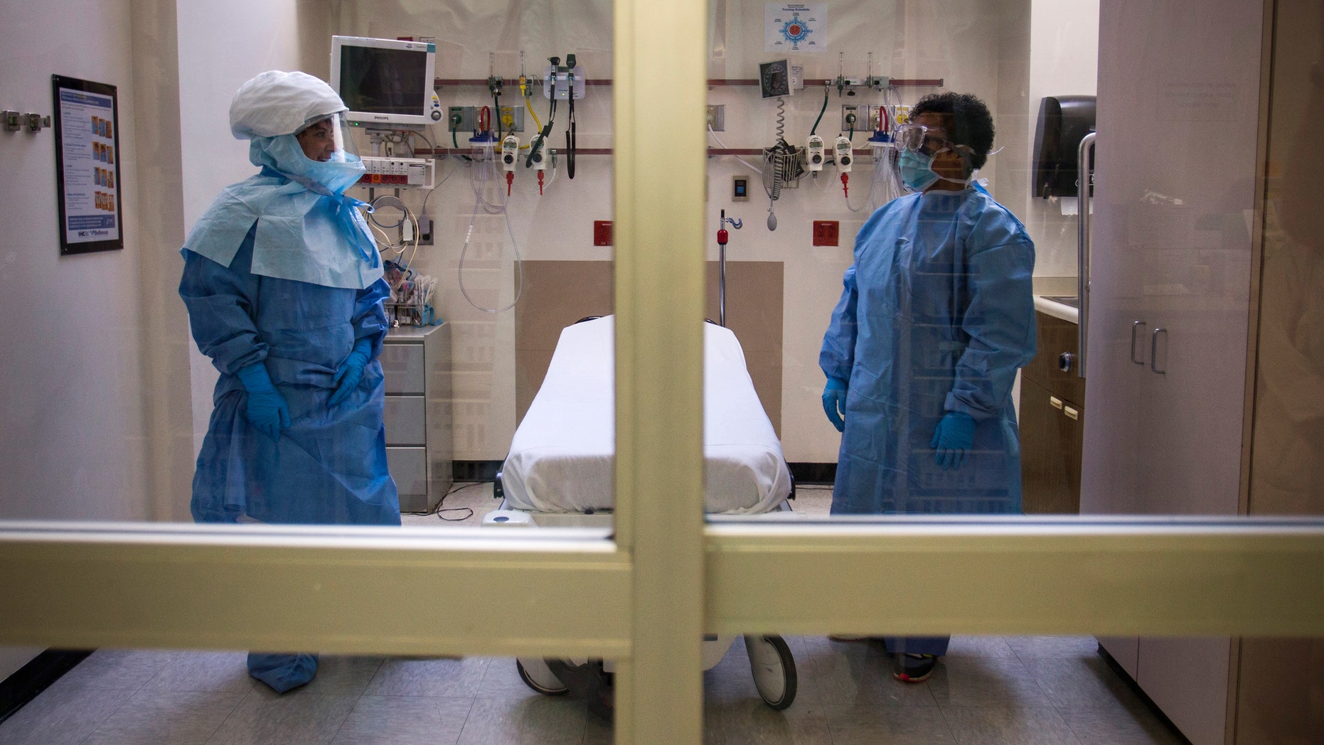 Health care workers display protective gear, which hospital staff would wear to protect them from Ebola infection, inside an isolation room as part of a media tour in the emergency department of Bellevue Hospital in Manhattan, New York October 8, 2014. REUTERS/Adrees Latif