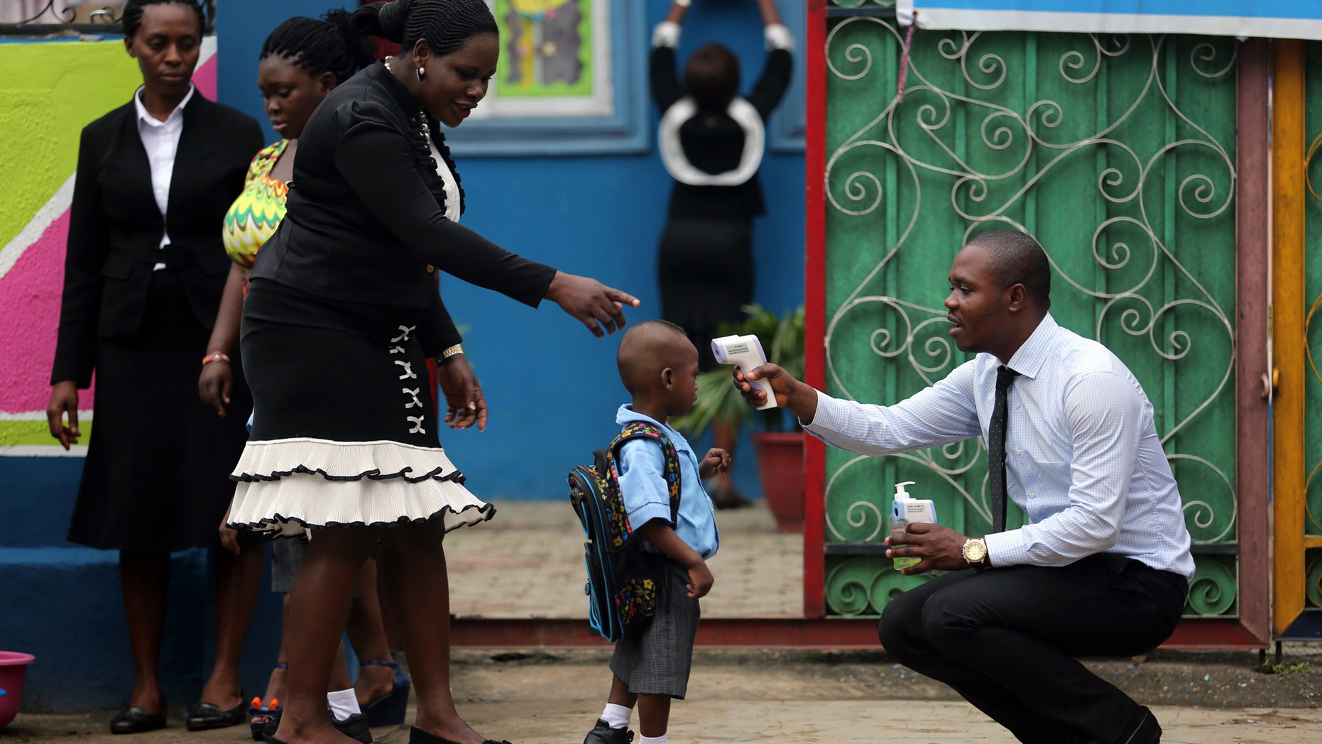 A school official takes a pupil's temperature using an infrared digital laser thermometer in front of the school premises, at the resumption of private schools, in Lagos in this September 22, 2014 file photo. REUTERS/Akintunde Akinleye