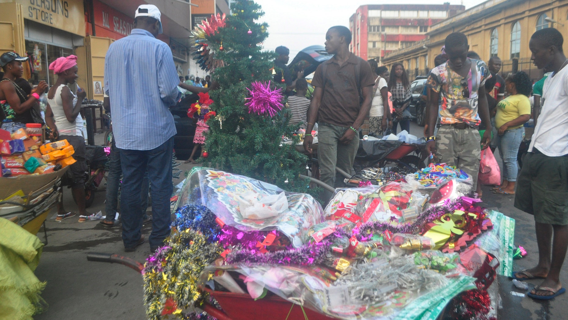 Liberian men shop for a Christmas tree in Monrovia, Liberia, Wednesday, Dec. 24, 2014. The deadly Ebola epidemic in Sierra Leone means no festive parties at the beach, no carolers singing at night. (AP Photo/Abbas Dulleh)