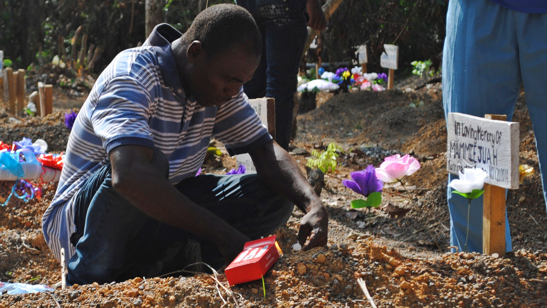 Survivor of Ebola virus Stanley Juah weeps at his son's grave at a cemetery for victims of Ebola virus in Suakoko, Liberia, March 11, 2015. Juah lost four of his family members and relatives to Ebola. REUTERS/James Giahyue