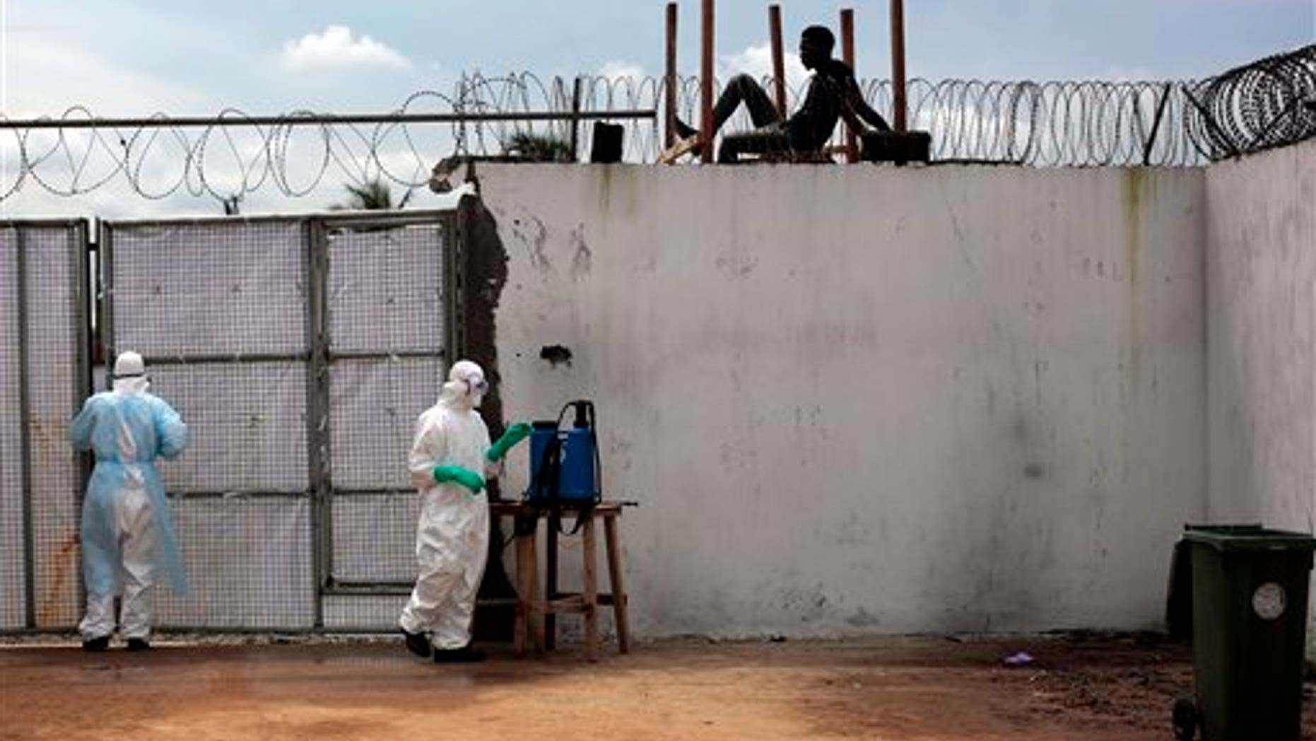 In this Friday, Sept. 26, 2014 file photo, health workers stand outside the Island Clinic Ebola isolation and treatment center in Monrovia, Liberia. (AP Photo/Jerome Delay, File)