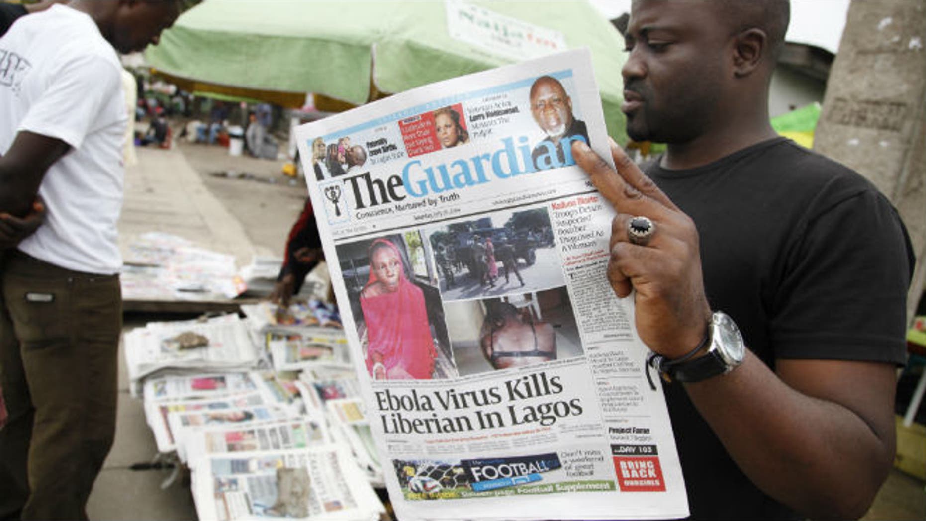 A man reads a local newspaperson a street with the headline Ebola Virus kills Liberian in Lagos, in Lagos Nigeria, Saturday, July 26, 2014. (AP Photo/Sunday Alamba)