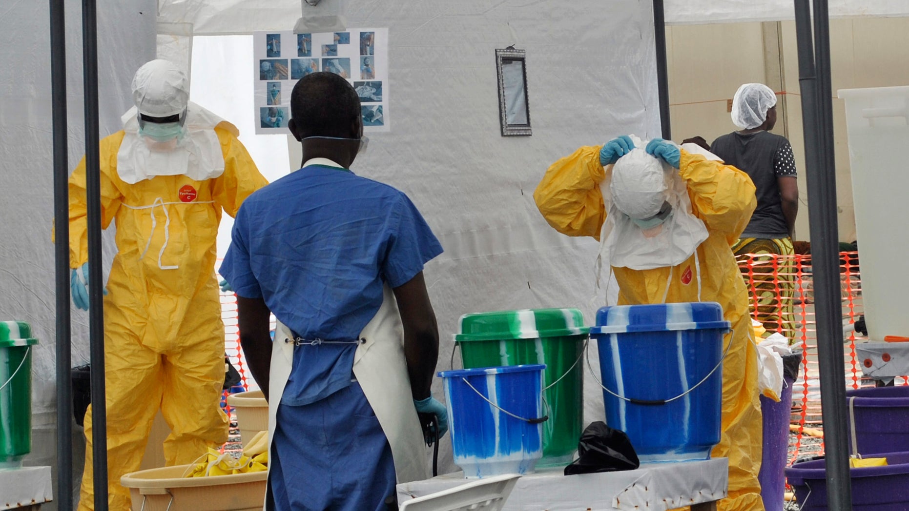 A Doctors Without Borders health worker takes off his protective gear under the surveillance of a colleague at a treatment facility for Ebola victims in Monrovia September 29, 2014. REUTERS/James Giahyue