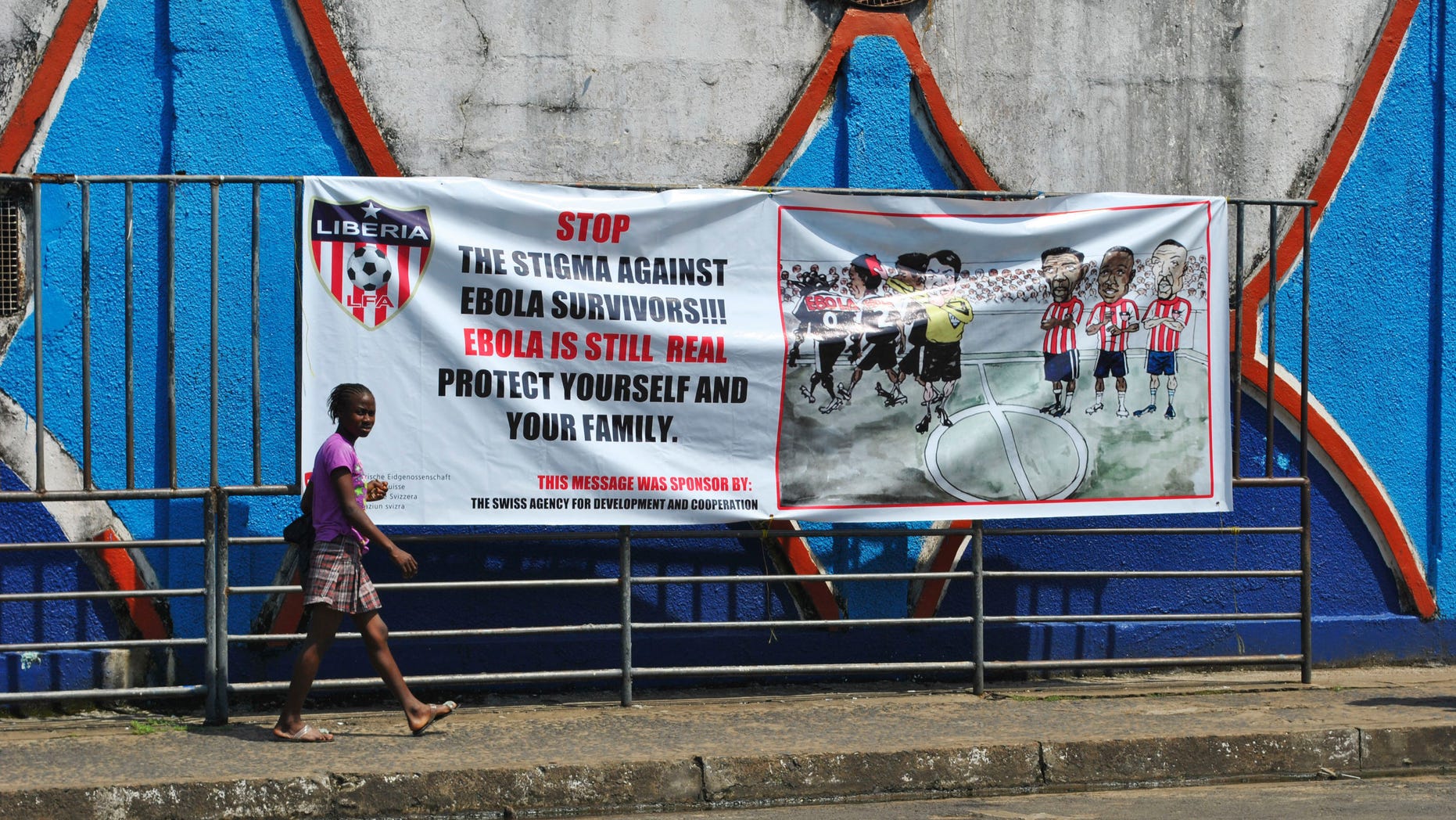 A woman walks pass an Ebola virus awareness campaign poster in Monrovia, December 8, 2014. REUTERS/James Giahyue