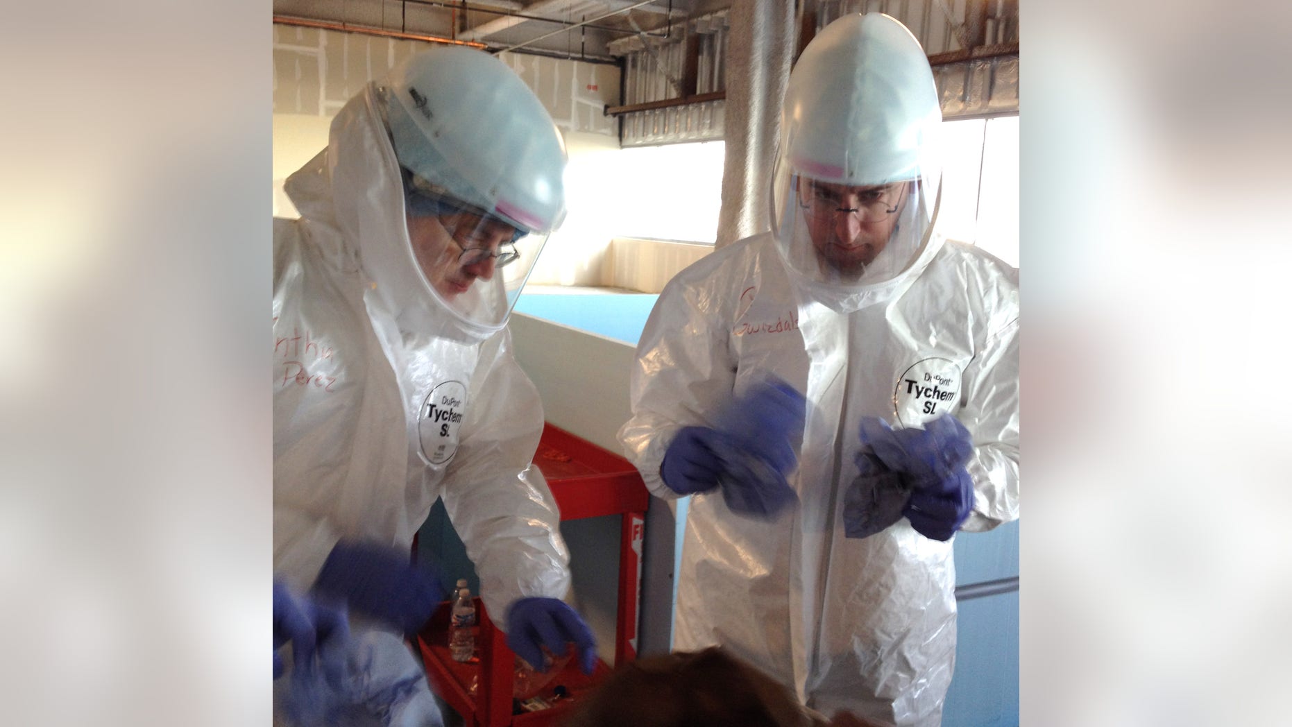 In this Monday, Oct. 6, 2014, photo Dr. Michael OConnor , left, and Dr. Mark Nunnally, learn how to use personal protective gear during Ebola preparedness training at the University of Chicago. (AP Photo/Lindsey Tanner)