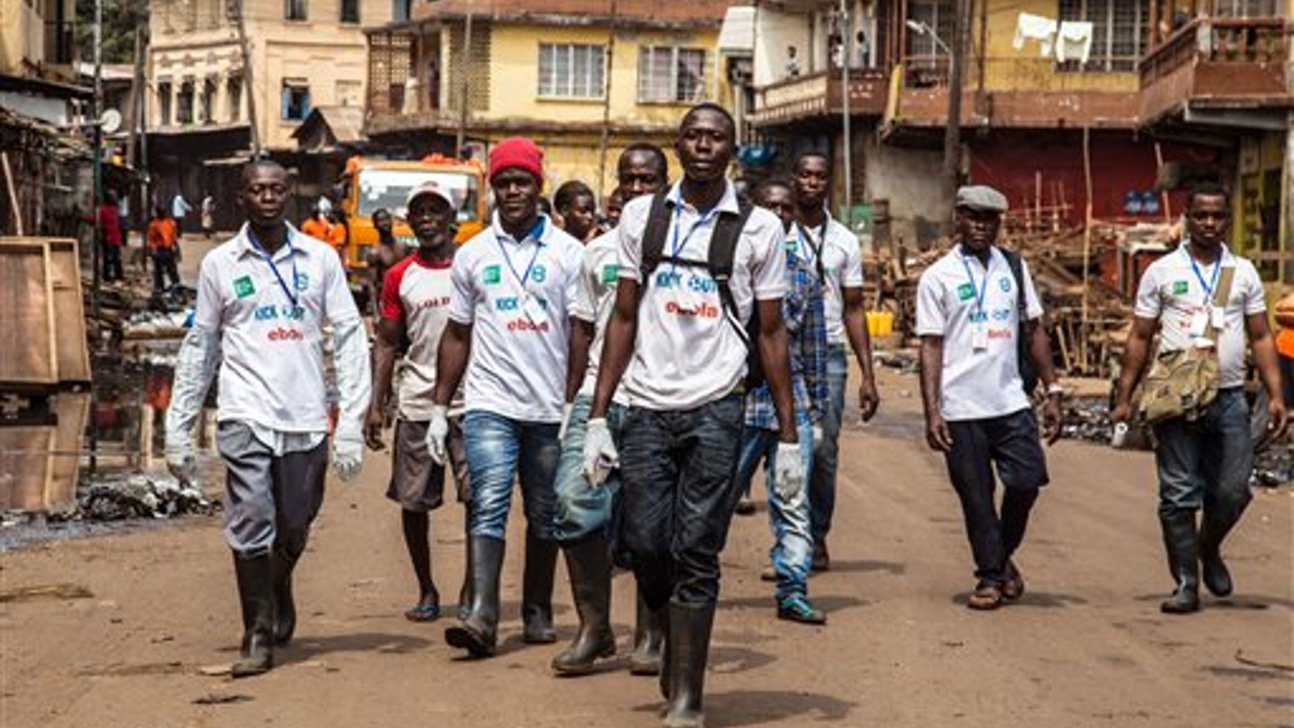 FILE - In this file photo taken on Friday, March. 27, 2015, a team of Sierra Leone health workers walk as they look for people suffering from Ebola virus symptoms or people they can educate about the virus as there country enters a three day country wide lockdown on movement of people do to the Ebola virus in the city of Freetown, Sierra Leone. (AP Photo/ Michael Duff,File)