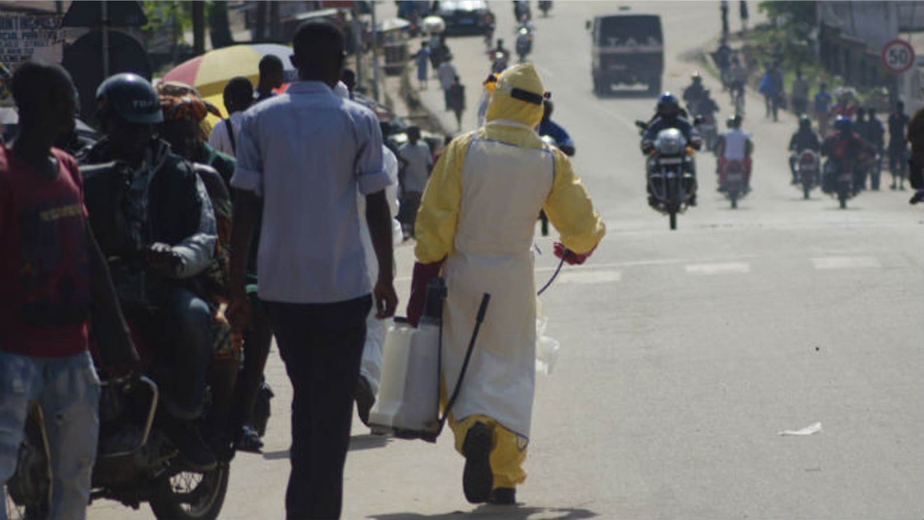 A health worker with disinfectant spray walks down a street outside the government hospital in Kenema, July 10, 2014. (REUTERS/TOMMY TRENCHARD)