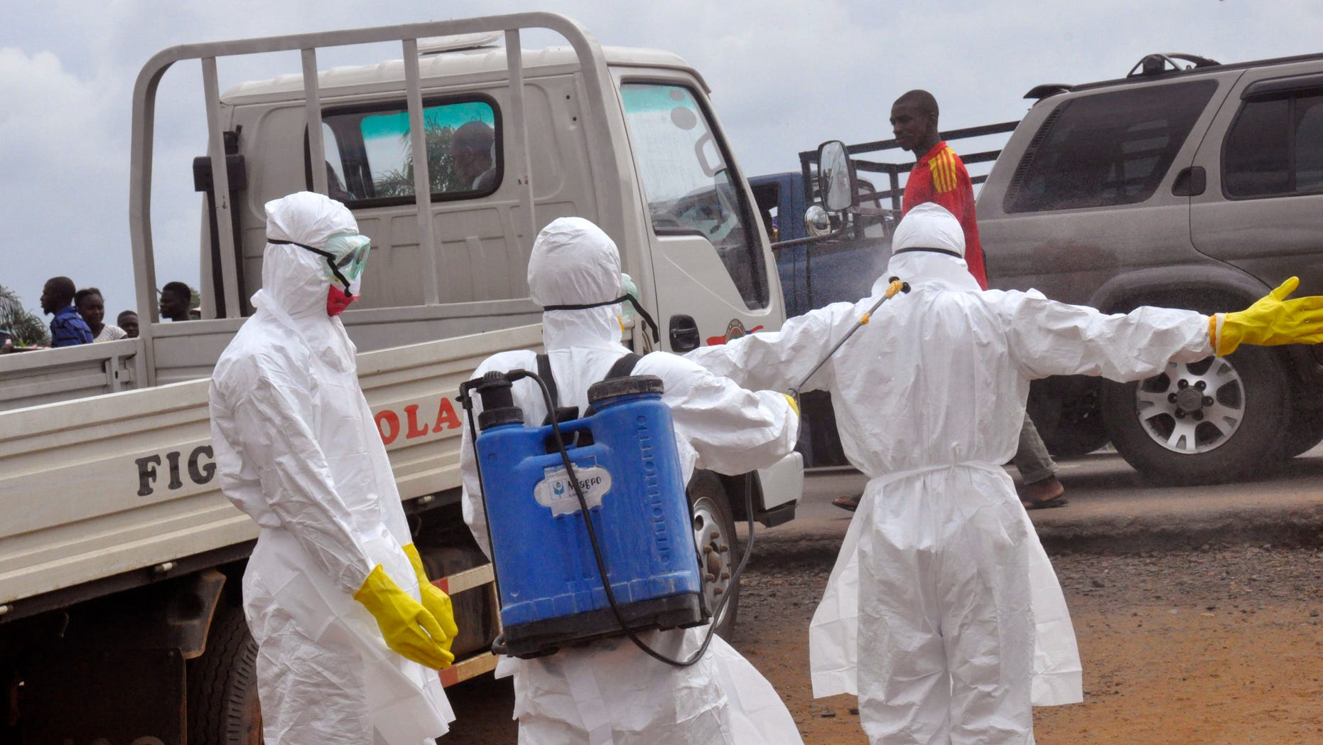 Health workers spray each other with disinfectant chemicals as they worked with a suspected Ebola virus death in Monrovia, Liberia, Thursday, Sept. 4, 2014. (AP Photo/Abbas Dulleh)