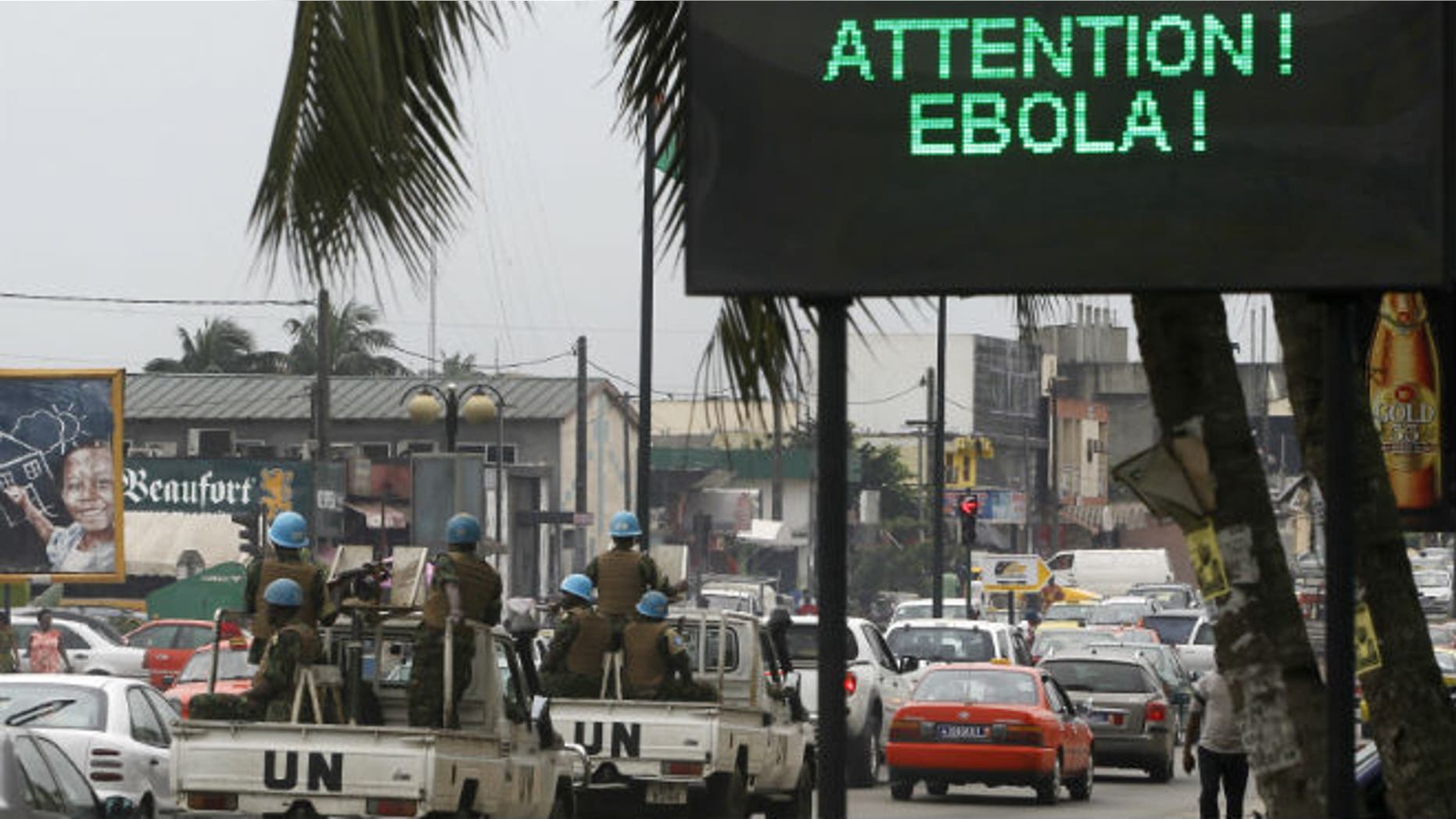 A U.N. convoy of soldiers passes a screen displaying a message on Ebola on a street in Abidjan August 14, 2014. REUTERS/Luc Gnago