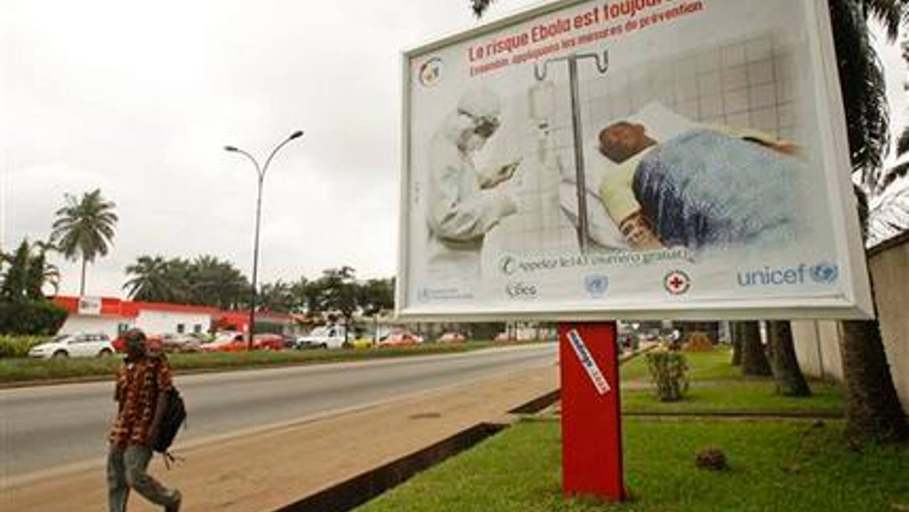 Aug. 25, 2014: A man, left, walk past a Ebola awareness campaign poster, in the city of Abidjan, Ivory Coast.