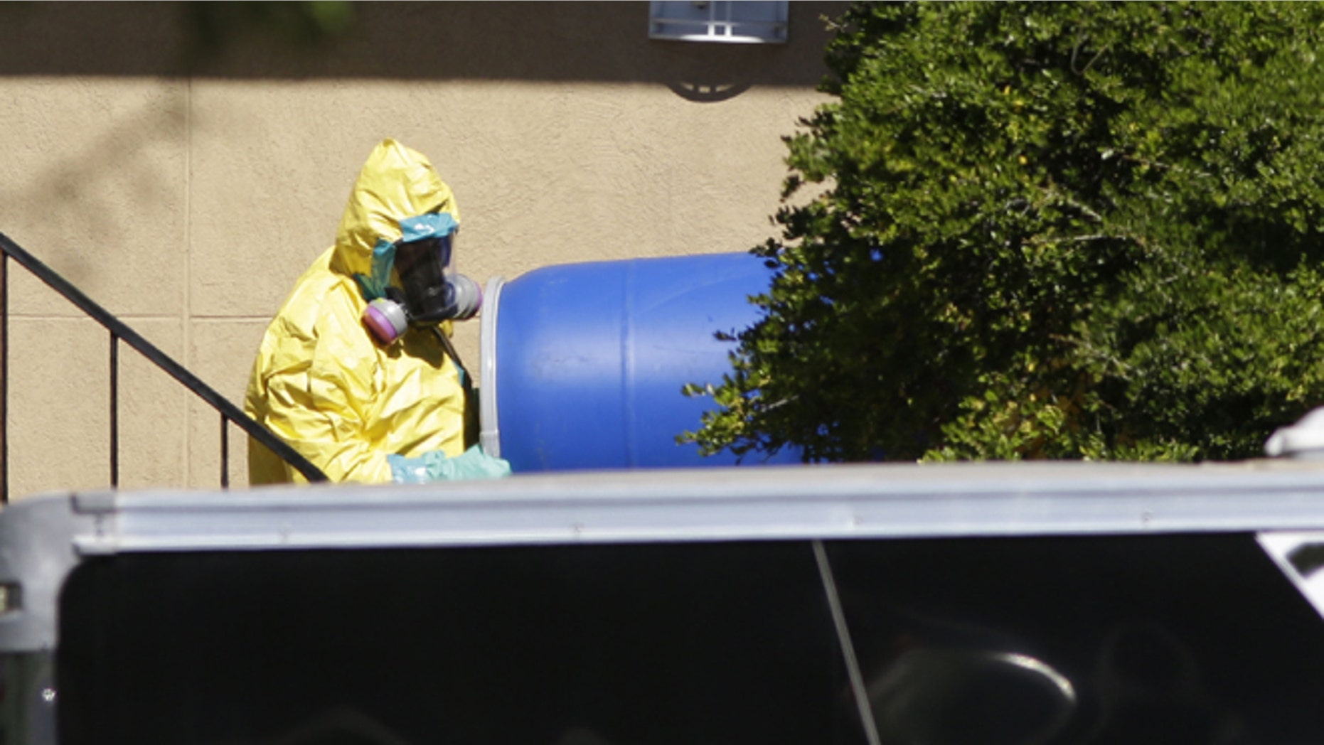 Oct. 3, 2014: A hazardous material cleaner removes a blue barrel from the apartment in Dallas. (AP)
