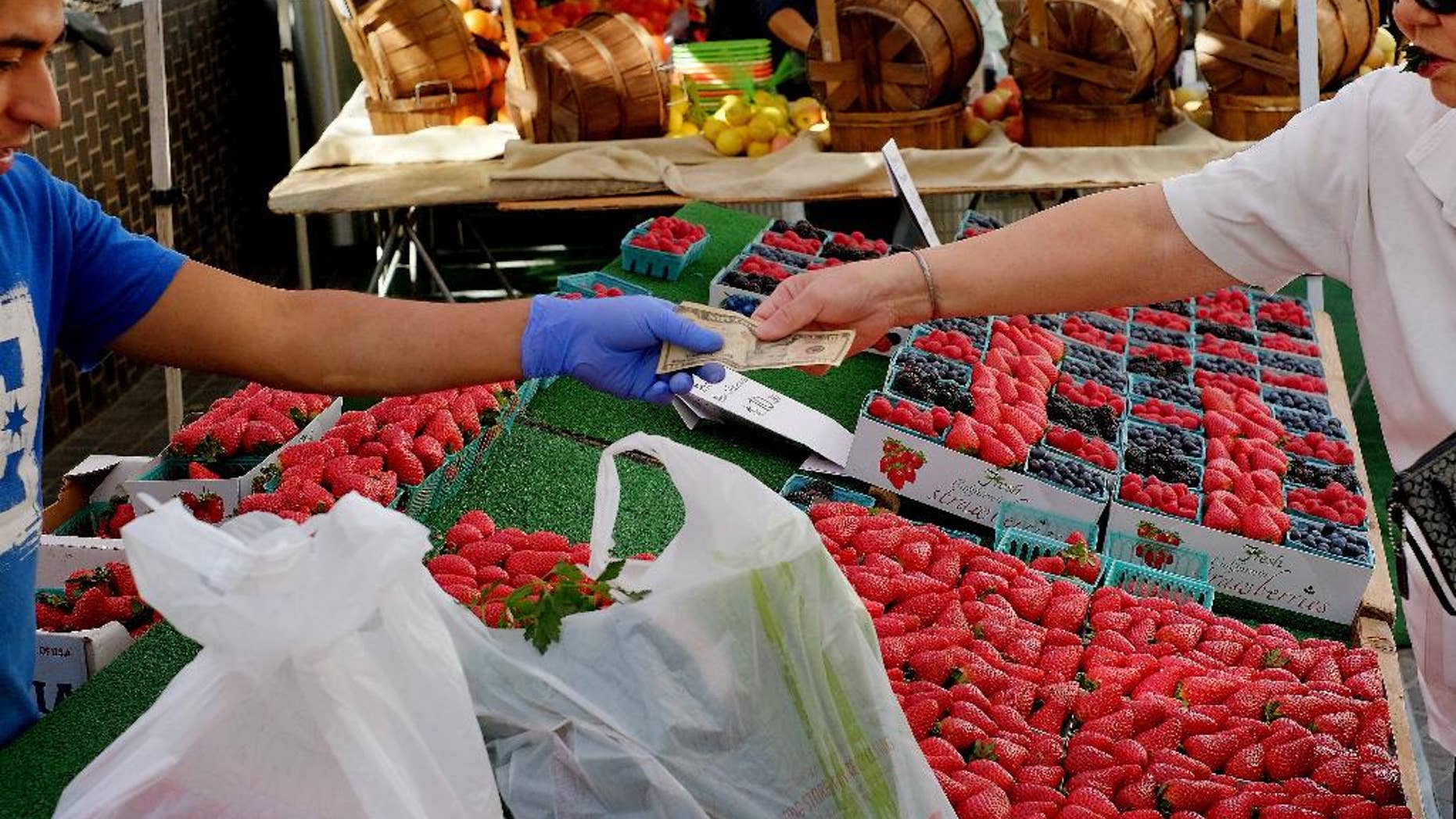 In this Friday, Feb. 6, 2015 photo, a shopper pays for produce at a Farmers Market in downtown Los Angeles. The Commerce Department releases its January report on consumer spending, which accounts for 70 percent of economic activity, on Monday, March 2, 2015. (AP Photo/Richard Vogel)
