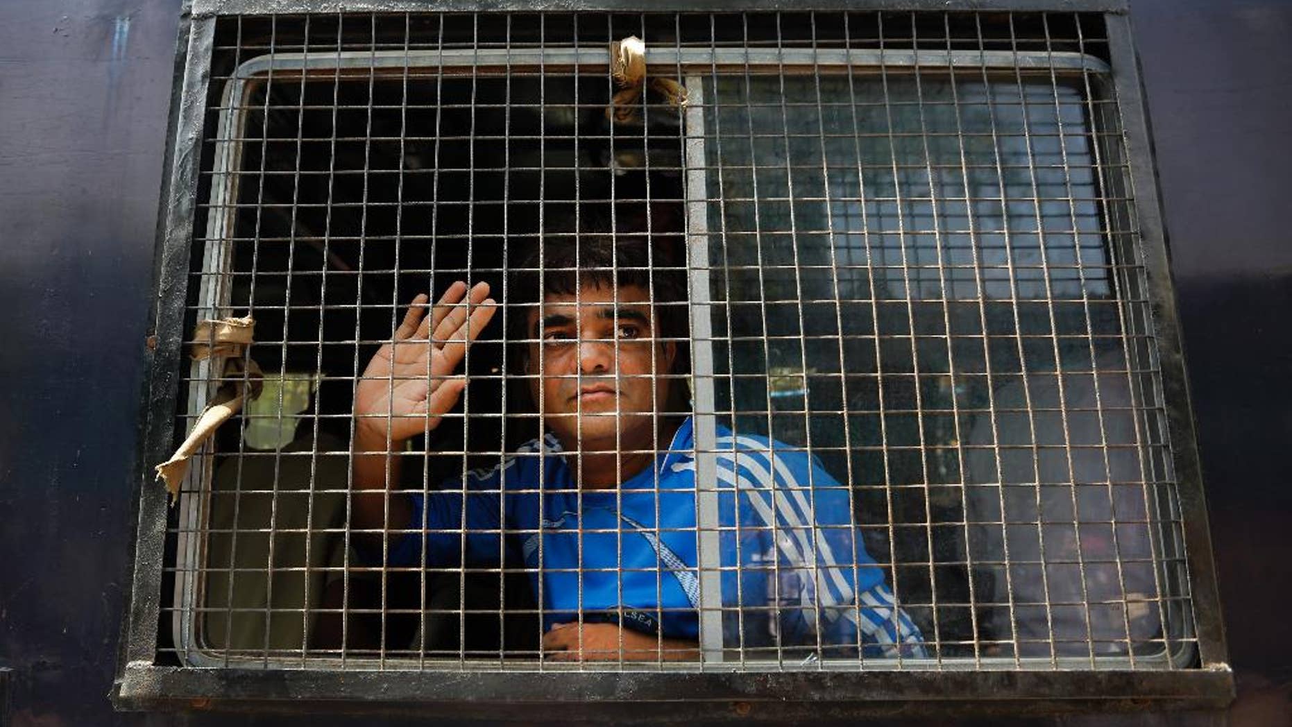 An unidentified Indian man accused on a 2002 riot case waves to supporters as he arrives at Ahmadabad's court, India, Thursday, June 2, 2016. The court convicted 24 suspects, 11 of them for murder, for their part in religious riots in 2002 in western India with riot-related cases moving slowly through a creaky legal system. India’s judicial system is notorious for delays. The most high profile convictions in 2002 religious riots came ten years later when Maya Kodnani, a former government minister, and 31 others were convicted on charges ranging from rioting to murder, stemming from an attack in Naroda Patiya, a small industrial town on the outskirts of Ahmadabad that killed 95 people. (AP Photo/Ajit Solanki)