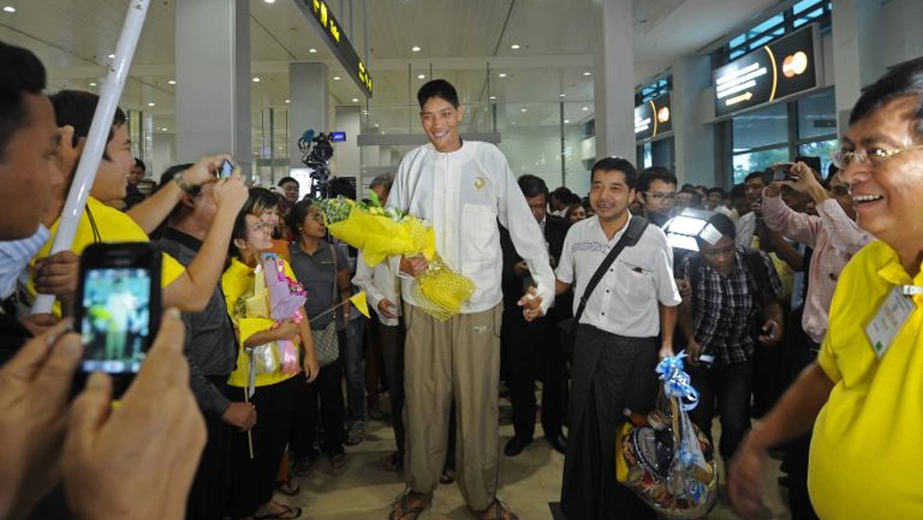 Win Zaw Oo (C) arrives from Singapore, at Yangon airport on September 26, 2013. At seven foot eight inches (233cm), Win Zaw Oo is believed to be the country's tallest man and arrived in Yangon after undergoing successful brain surgery.