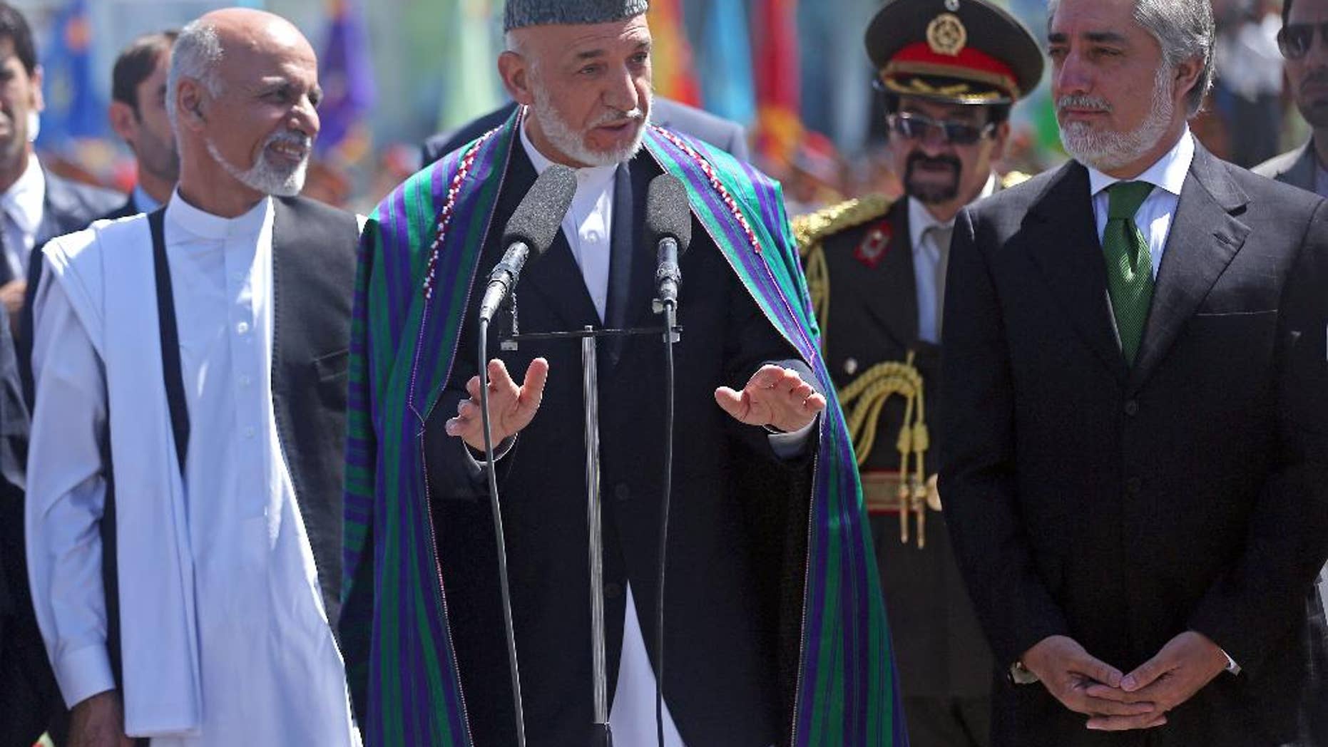 Afghan President Hamid Karzai, center, speaks in front of local and international media representatives as presidential candidates Abdullah Abdullah, right, and Ashraf Ghani Ahmadzai, left , listen during the Independence Day ceremony in Kabul, Afghanistan, Tuesday, Aug. 19, 2014. King Amanullah won the country's independency from Britain in 1919. (AP Photo/Massoud Hossaini)