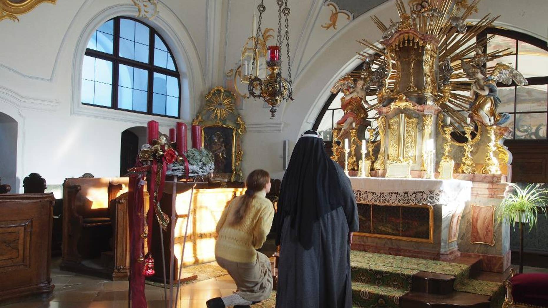 FILE - In this Dec. 6, 2016 file photo Sister Apollonia, right, and Postulant Claudia Schwarz kneel in front of the altar of the chapel of the abbey in Altomuenster, Germany. Bavarian Catholic church authorities said Thursday, Jan. 19, 2017 they have closed Germany’s last Bridgettine Order abbey at the request of the Vatican _ renewing concerns about what will happen to the property, including a precious library, which now goes to the local diocese. (AP Photo/David Rising, file)