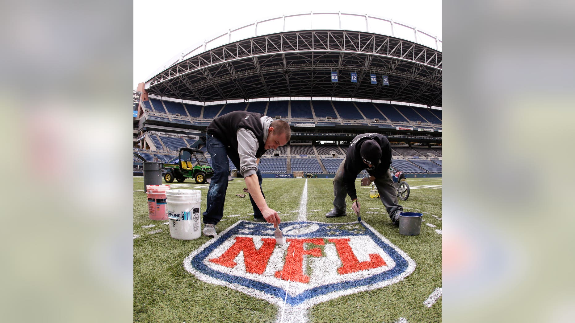 In this photo made with a fisheye lens, Austin Amon, left, and Ryan Johnson, right, paint an NFL championship logo Tuesday, Jan. 14, 2014, in Seattle as they prepare CenturyLink Field for Sunday's NFL football NFC championship game between the Seattle Seahawks and the San Francisco 49ers. (AP Photo/Ted S. Warren)