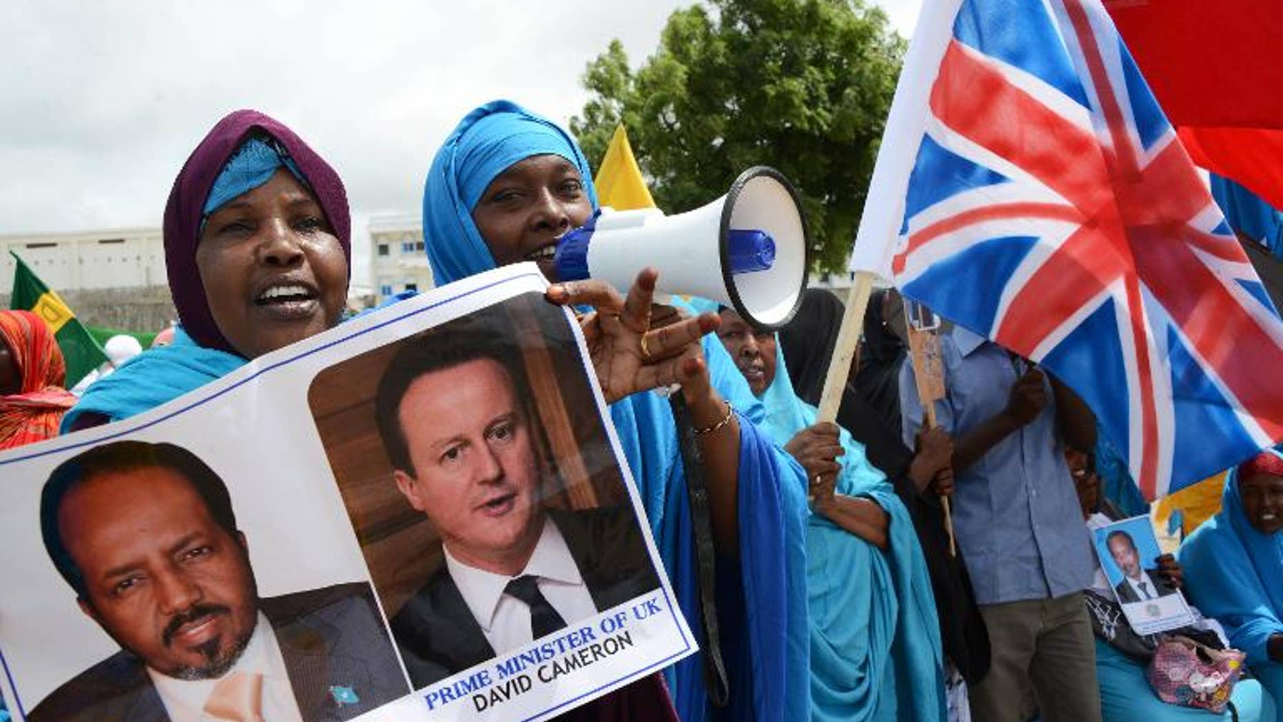 A Somali woman holds images of Britain's Prime Minister David Cameron and Somali President Hassan Sheikh Mohamud in Mogadishu, on May 7, 2013