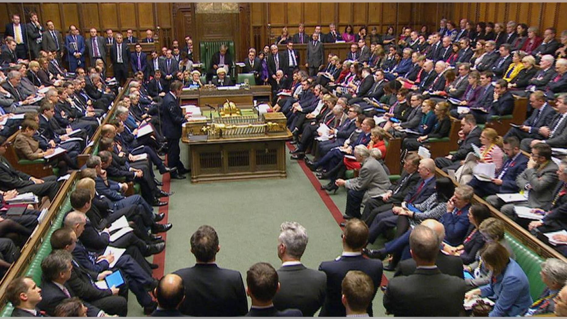 British Prime Minister David Cameron, standing centre left, talks to lawmakers inside the House of Commons in London during a debate on launching airstrikes against Islamic State extremists inside Syria, Wednesday, Dec. 2, 2015. The parliamentary vote is expected Wednesday evening. Opposition Labour Party leader, Jeremy Corbyn, looks at papers sitting centre right opposite Cameron, who opposes any expansion of Britain's military role. (Parliamentary Recording Unit via AP Video) TV OUT - NO ARCHIVE
