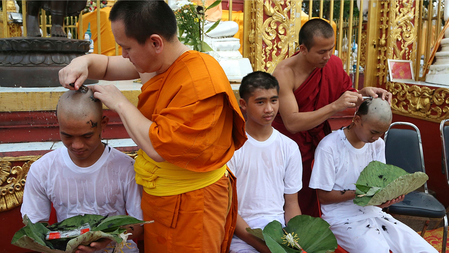 Soccer coach Ekkapol Chantawong, left, and teammates who were rescued last week from a flooded cave have their heads shaved in a traditional Buddhist ceremony in Mae Sai district, Chiang Rai province, northern Thailand.
