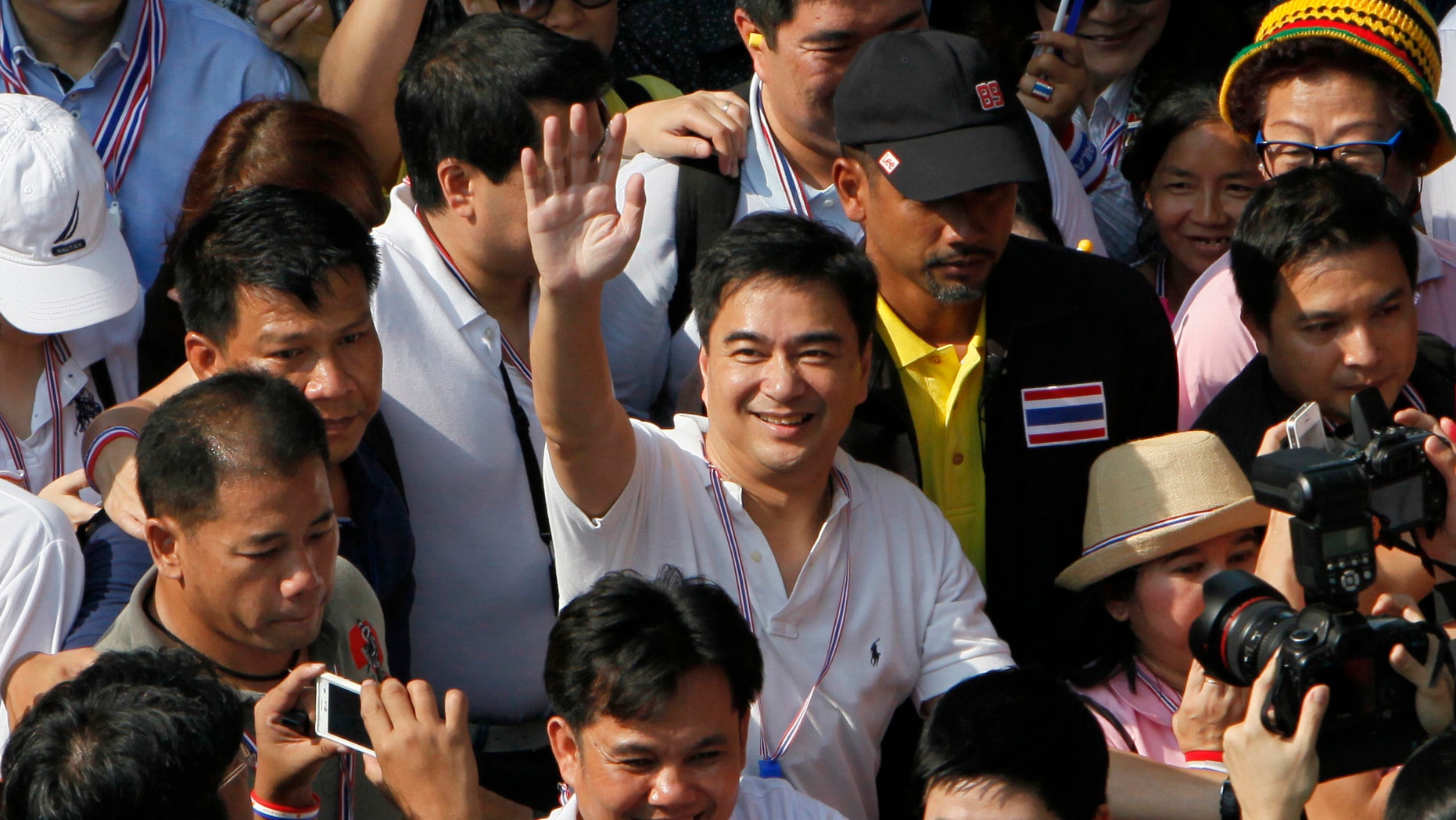 FILE - In this Monday, Dec. 9, 2013 file photo, Democrat leader and former Prime Minister Abhisit Vejjajiva, center, waves as he marches with anti-government protesters in Bangkok. Thailand's opposition Democrat Party has re-elected former Prime Minister Abhisit Vejjajiva its leader ahead of a crucial decision over whether to boycott an upcoming general election. Party spokesman Chavanond Intarakomalyasut confirmed Abhisit's selection Tuesday, Dec. 17, passed by almost unanimous vote. (AP Photo/Greg Baker, File)