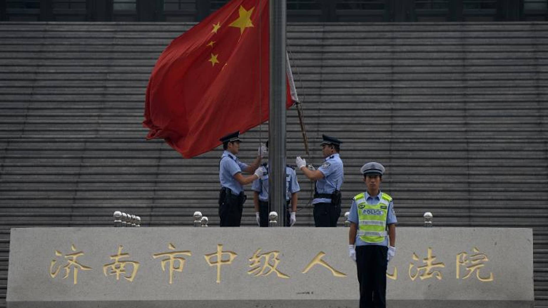 Police raise the Chinese flag outside the Intermediate People's Court in Jinan, Shandong Province on September 22, 2013