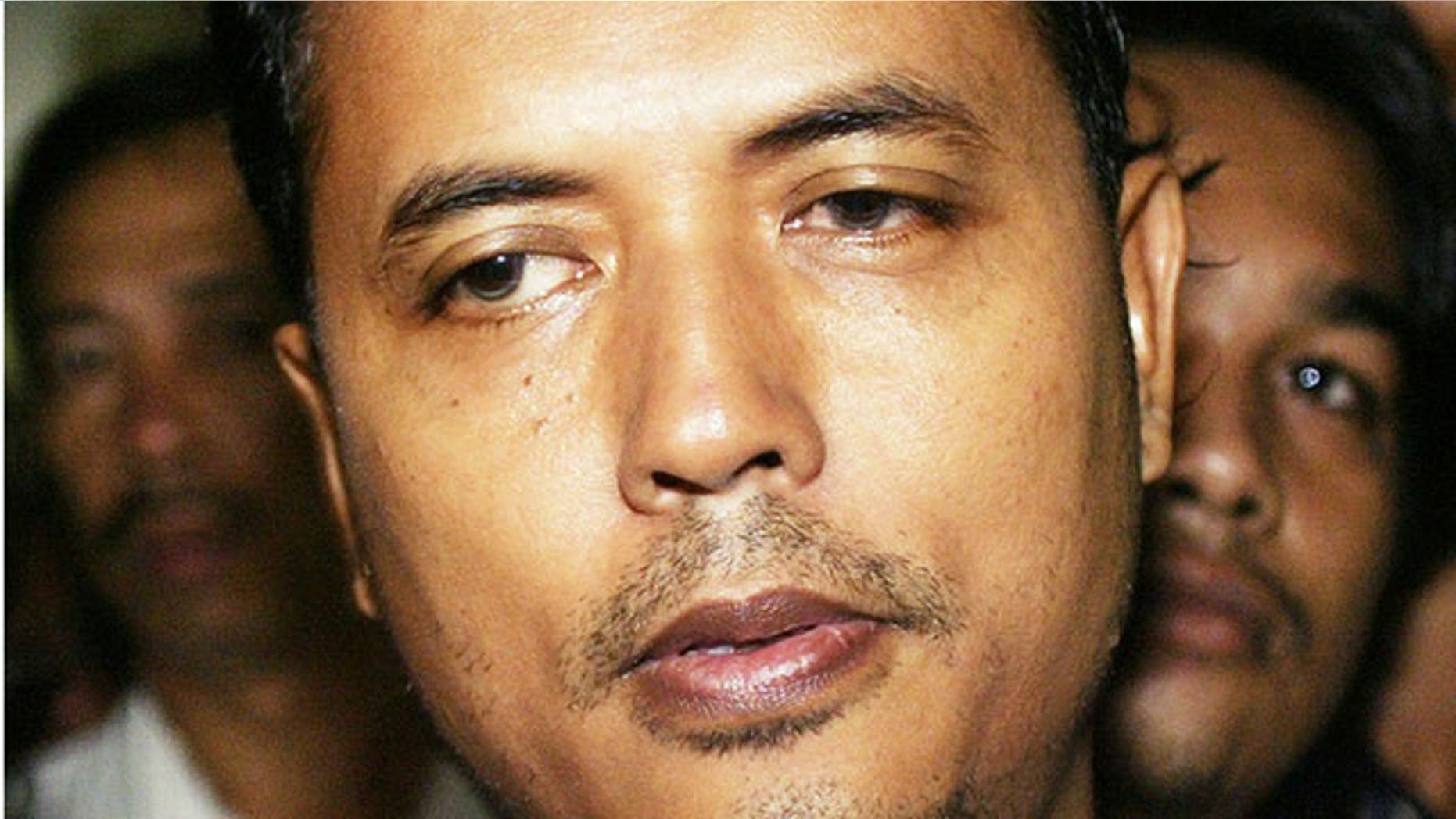 In this Feb. 4, 2003 file photo, terrorist suspect Mas Selamat Kastari is escorted by Indonesian Police officers into the Tanjung Pinang police station in Tanjung Pinang, on the Indonesian resort island of Bintan off the coast of Singapore. Malaysia deported the Singaporean terrorist suspect Friday, Sept. 24, 2010, nearly 18 months after he was captured while on the run after staging a dramatic escape from a high-security prison in the city-state.