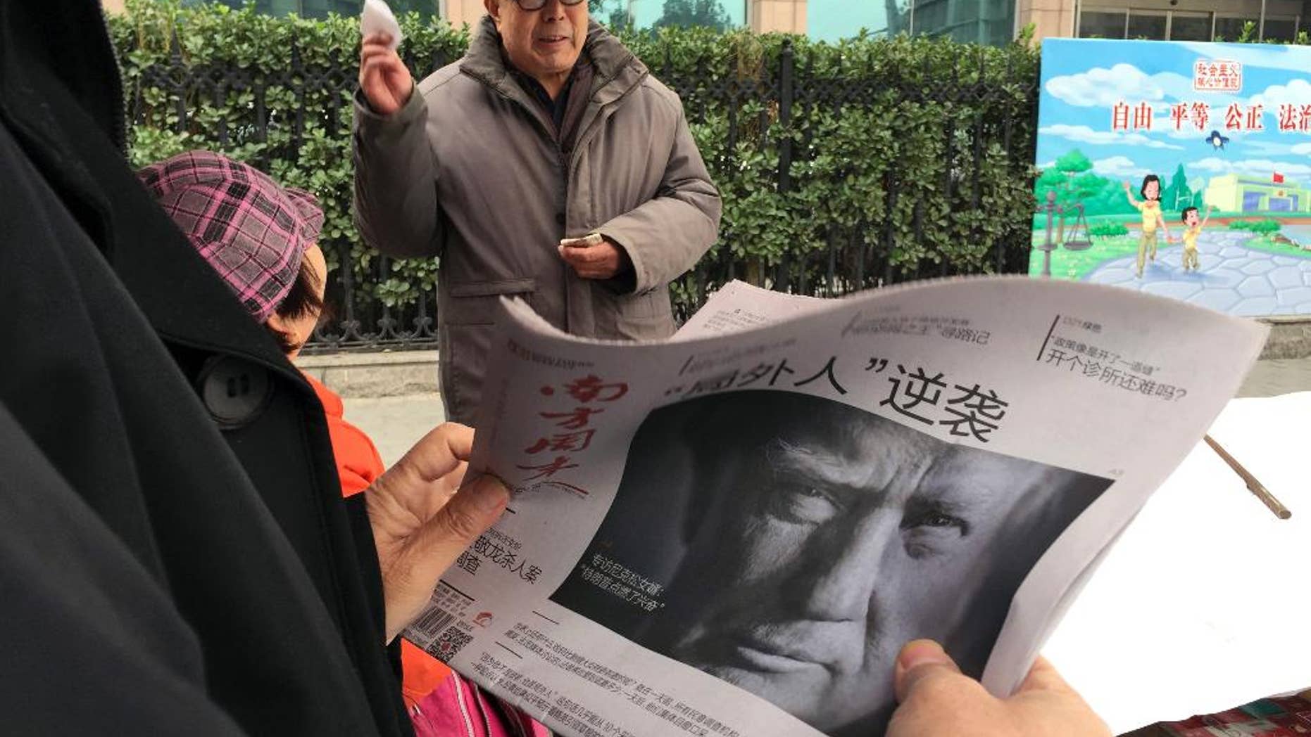 FILE - In this Nov. 10, 2016 file photo, a Chinese man holds up a Chinese newspaper with the front page photo of U.S. President-elect Donald Trump and the headline "Outsider counter attack" at a newsstand in Beijing, China. China views a Trump presidency with less trepidation. Citizens of China's capital Beijing on Saturday are expressing doubts about U.S. President Donald Trump's ability to steer the U.S. economy and manage China-American relations. (AP Photo/Ng Han Guan, File)