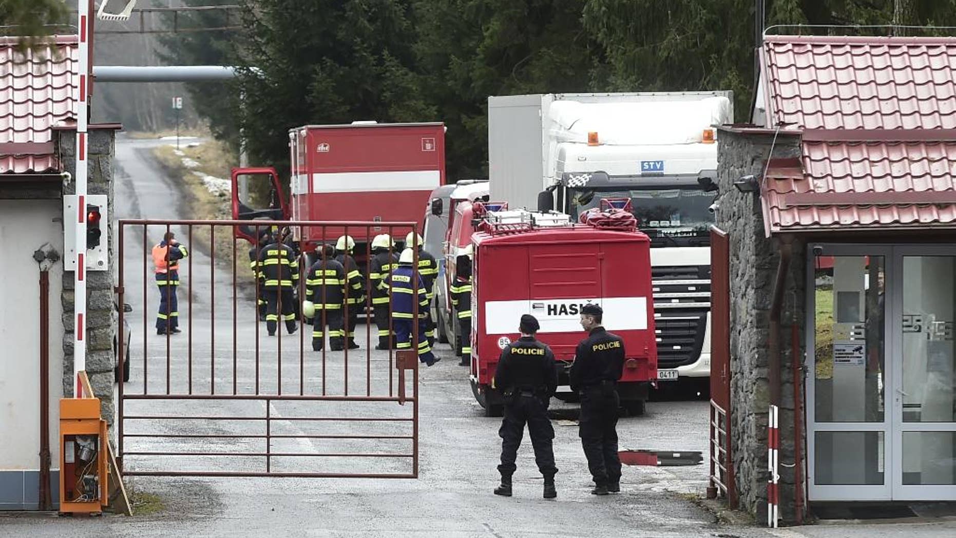 Two police officers watch over a gate as firemen stand nearby in the machinery plant Policske Strojirny where explosions have injured several people in Policka, 154 kilometers South East of Prague on Thursday, Feb. 23, 2017. (Josef Vostarek/CTK via AP)