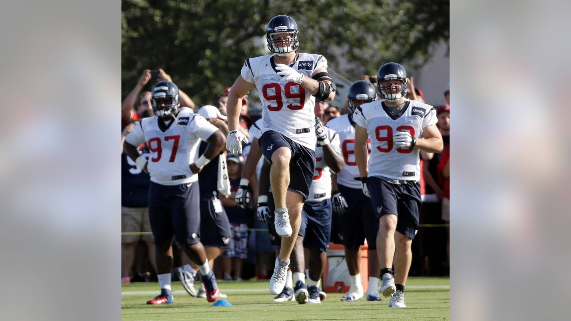 FILE - In this July 27, 2014 file photo, Houston Texans defensive end J.J. Watt (99) stretches with teammates during an NFL football training camp practice in Houston. Watt knows it's cliche to say "we're working hard every day" and he's "just trying to be a good teammate."(AP Photo/David J. Phillip, File)