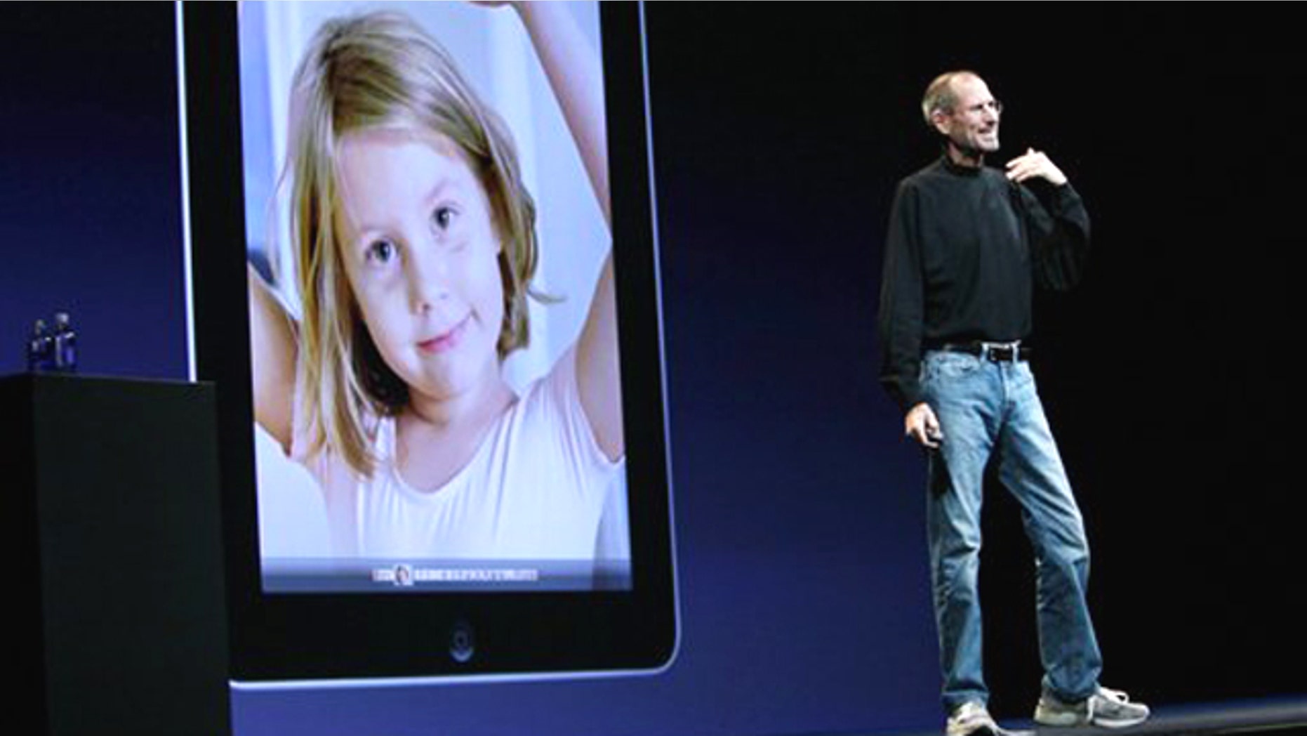 Apple CEO Steve Jobs, with the Apple iPad displayed over his shoulder, delivers the keynote address during the Apple Worldwide Developers Conference, Monday, June 7, 2010, in San Francisco.