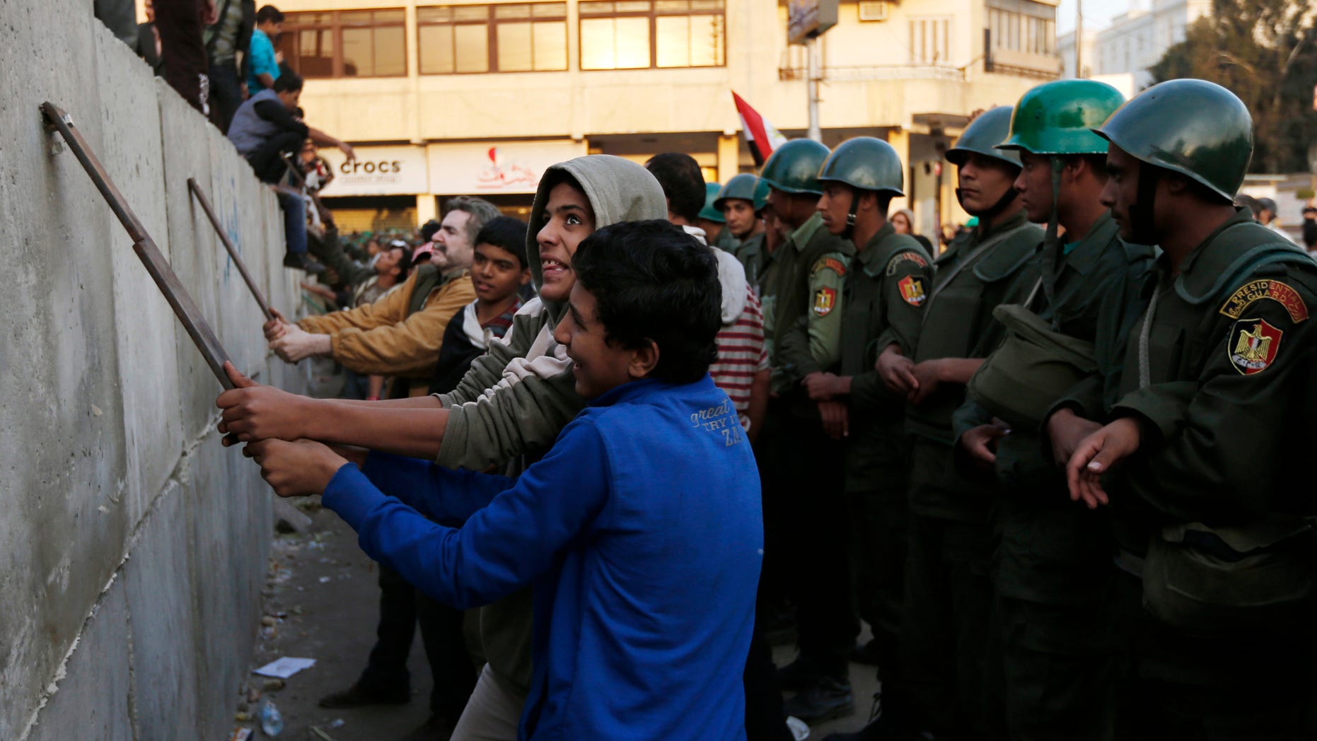 Dec. 9, 2012: Protesters break iron bars on cement blocks, as Egyptian army soldiers stand guard in front of the presidential palace in Cairo, Egypt.
