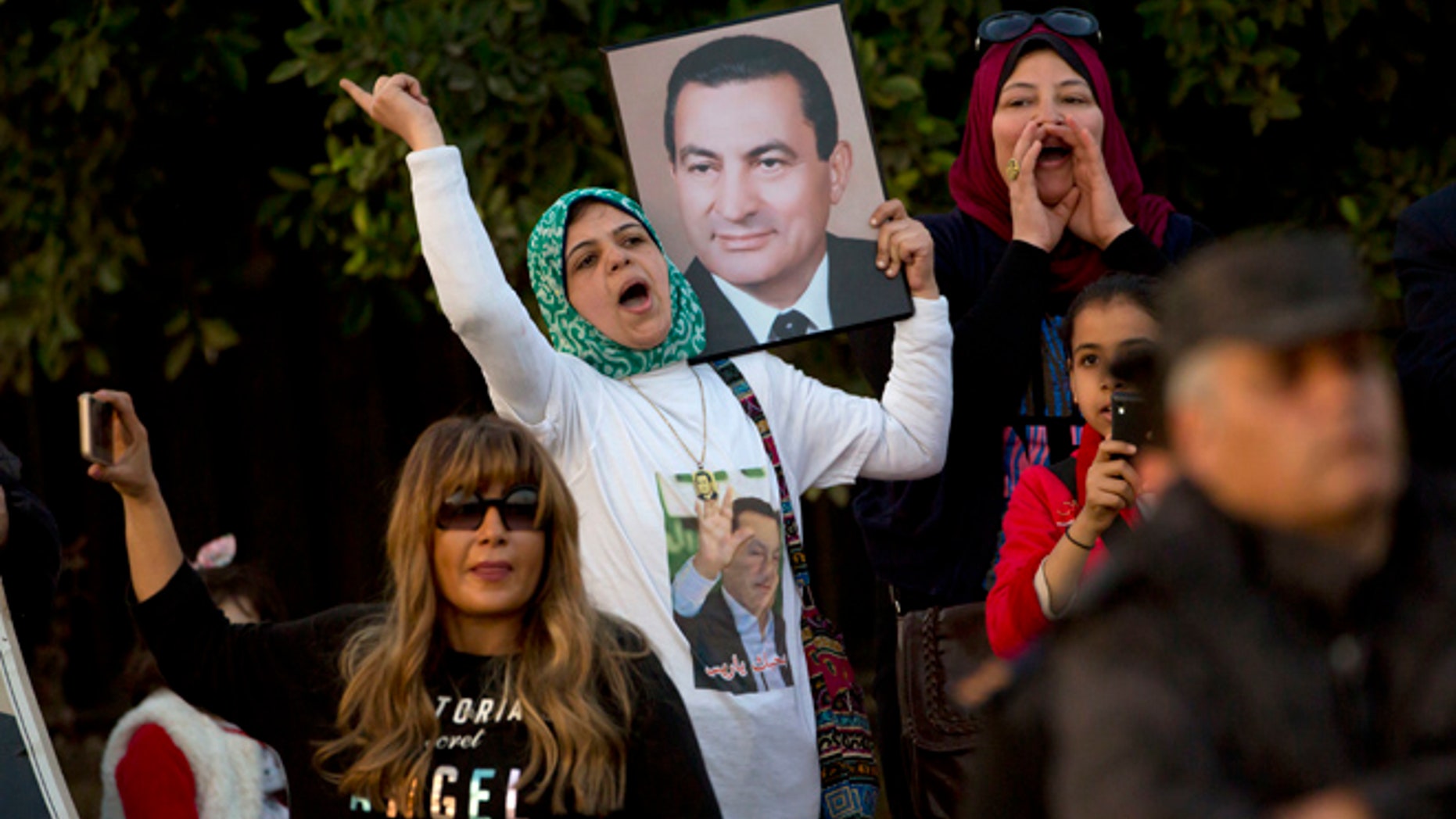 A small number of supporters of ousted former Egyptian President Hosni Mubarak hold posters with his photo, as they celebrate outside Maadi Military Hospital, where he is hospitalized, in Cairo, Egypt, Thursday, March 2, 2017.