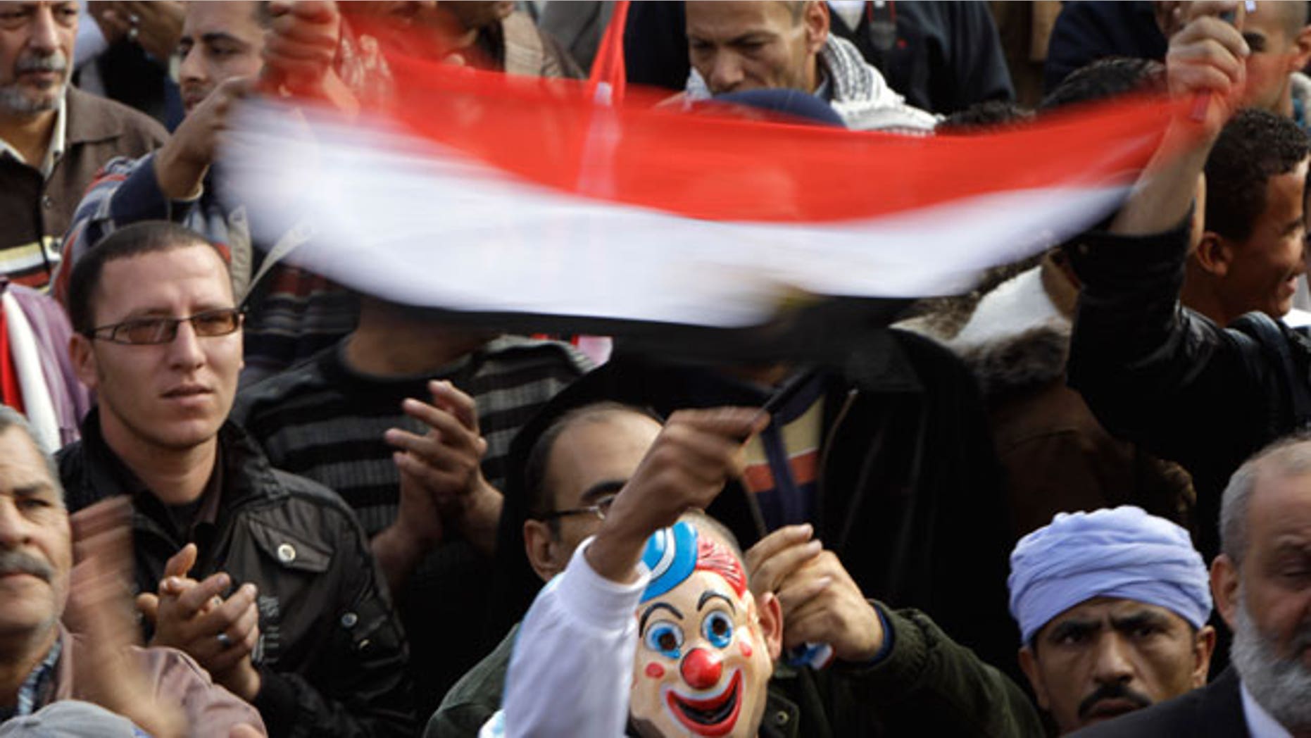 Dec. 1, 2011: An Egyptian waves a national flag while wearing a clown mask during a rally in support of the ruling supreme council of the armed forces, SCAF, at Abbasiya Square, in Cairo, Egypt.