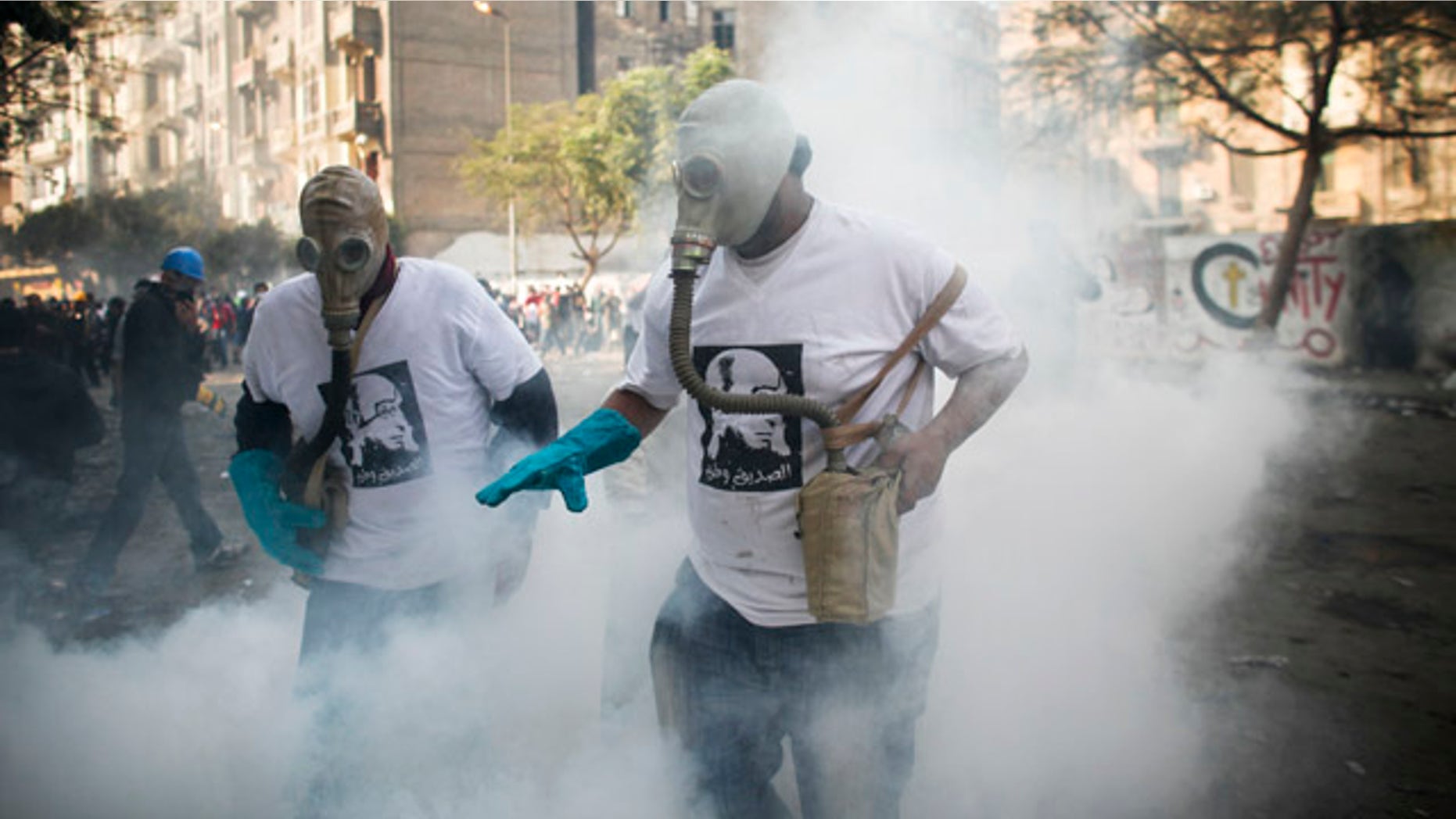 Nov. 23. 2011: Protesters attempt to get rid of a tear gas canister during clashes with Egyptian riot police, not pictured, near Tahrir square in Cairo, Egypt.
